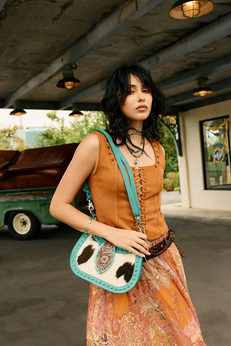 Woman holding a cow print handbag in an outdoor setting