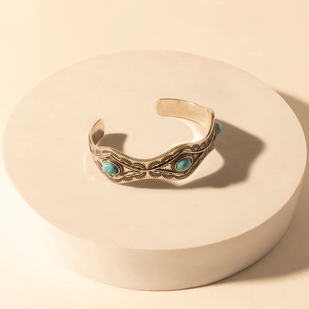 Decorative bracelet with turquoise stones on a beige stand