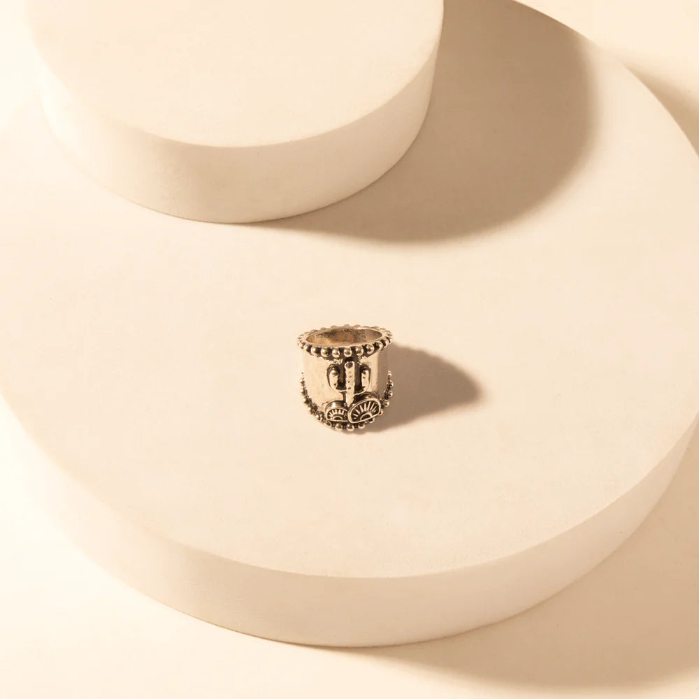 Gold beaded ring on a beige surface with soft shadows