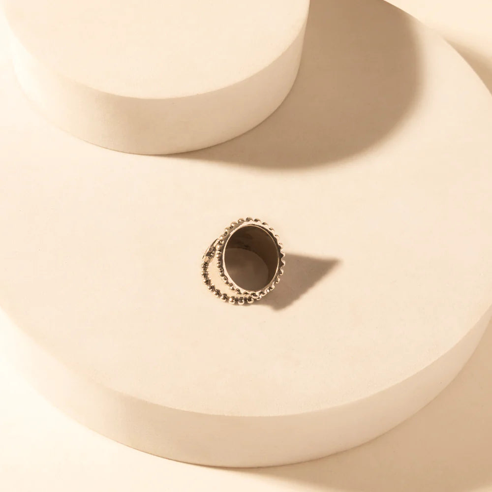 Gold ring with intricate design on a beige surface