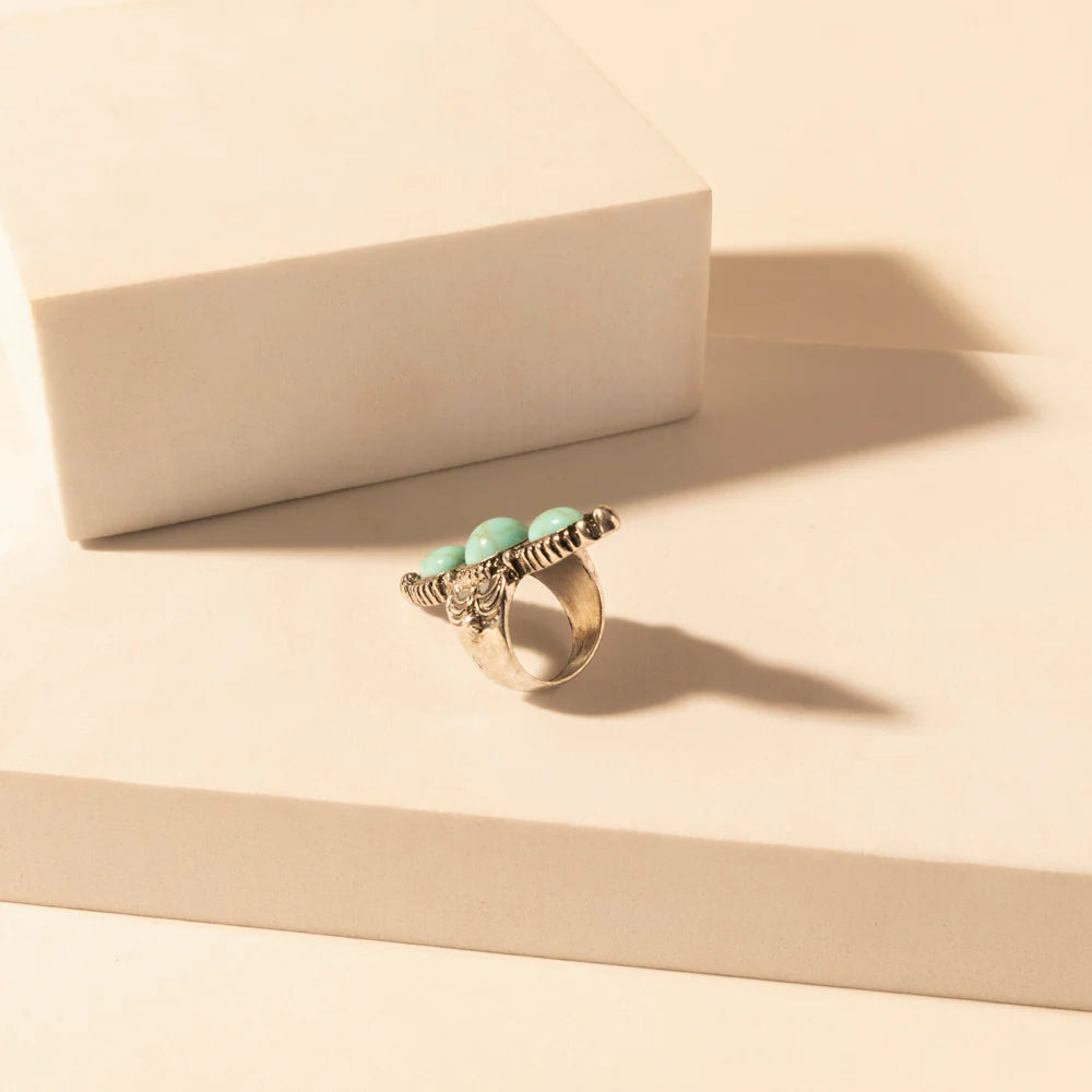 Silver ring with turquoise stones on a beige surface