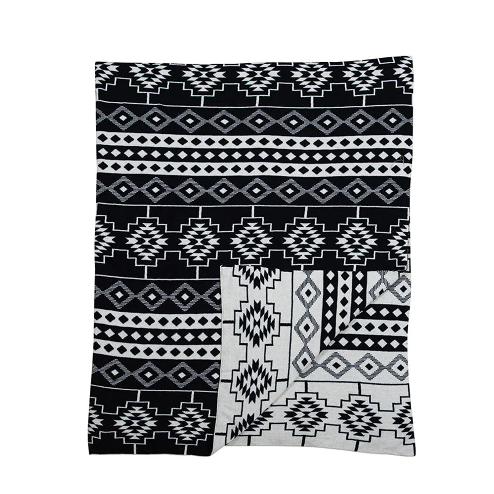Azteca Ridge Throw. A throw blanket with geometric patterns, featuring black and white colors on a flat surface.