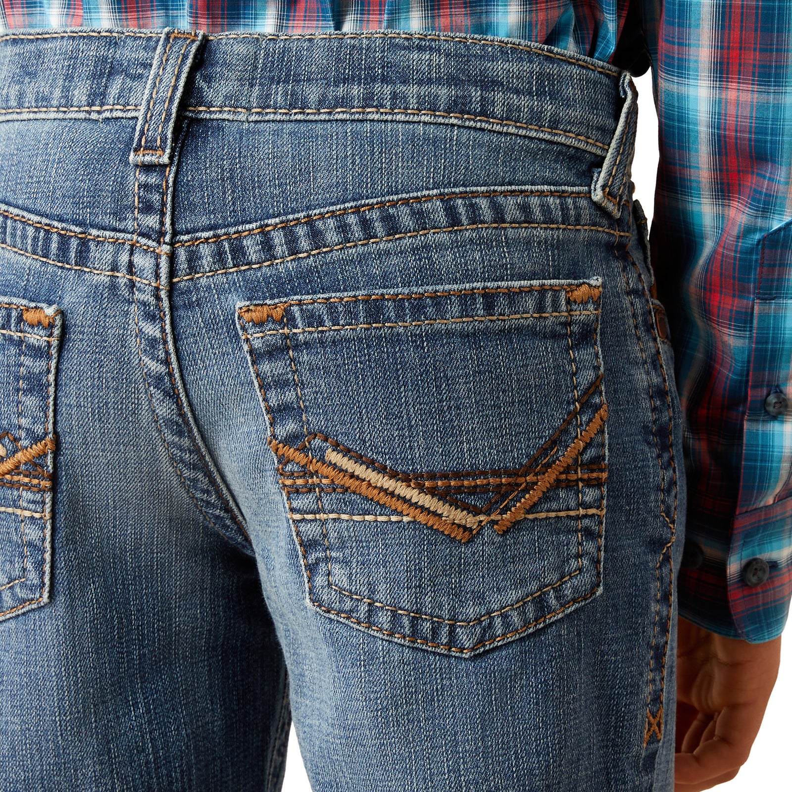 Ariat Boy's B5 Slim Bennet Straight Leg Jean. Close-up of blue jeans with decorative stitching on the back pocket, worn by a person in a plaid shirt.