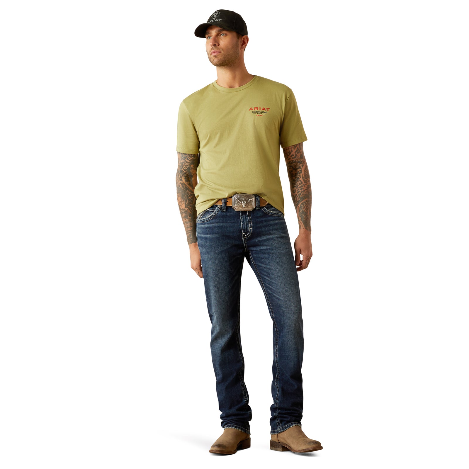 Ariat Men's M8 Modern Matthew Straight Leg Jean. Man wearing a green t-shirt, blue jeans, and a black cap on a white background