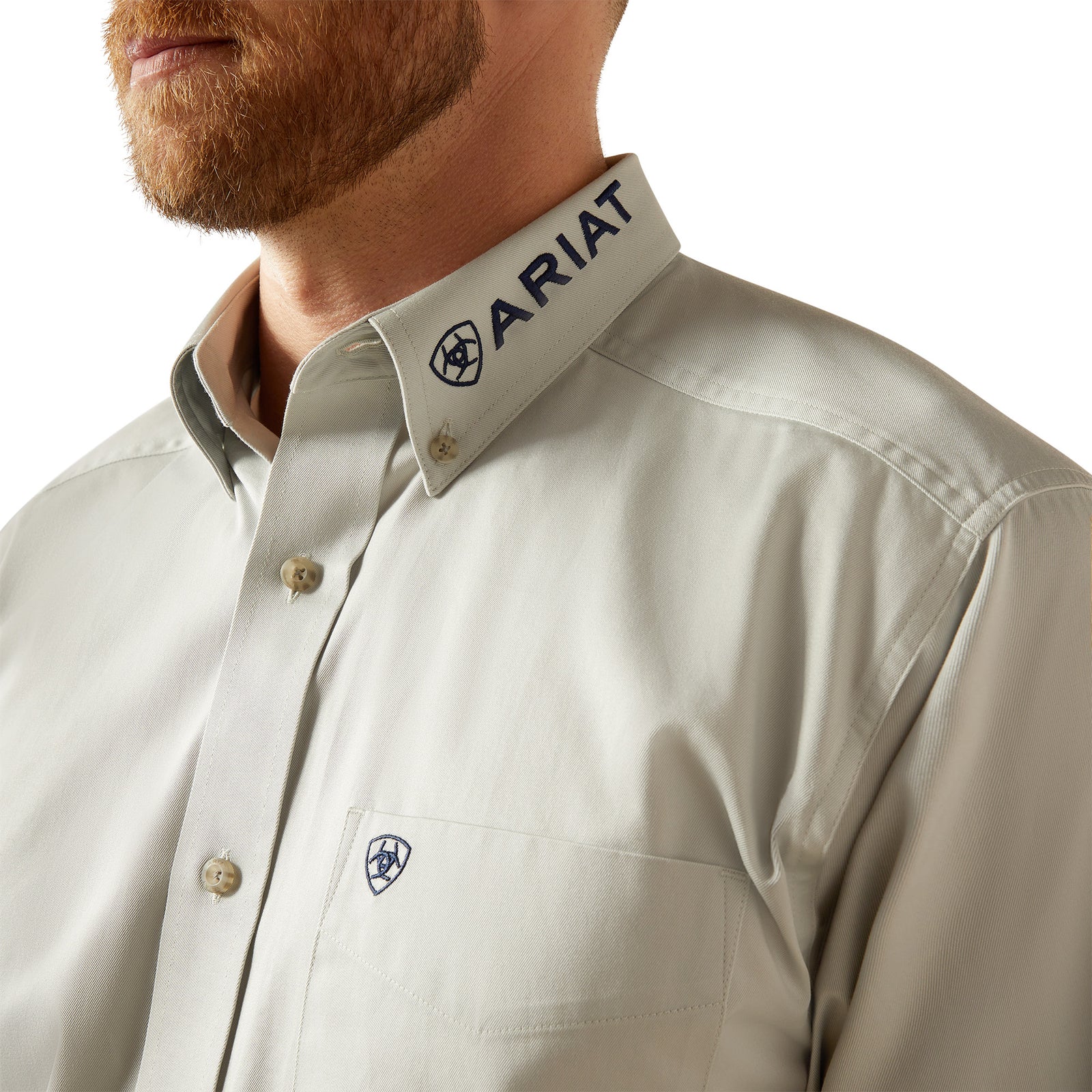 Ariat Men's Team Logo Twill L/S Western Shirt. Close-up of a beige shirt with Ariat logo on a white background