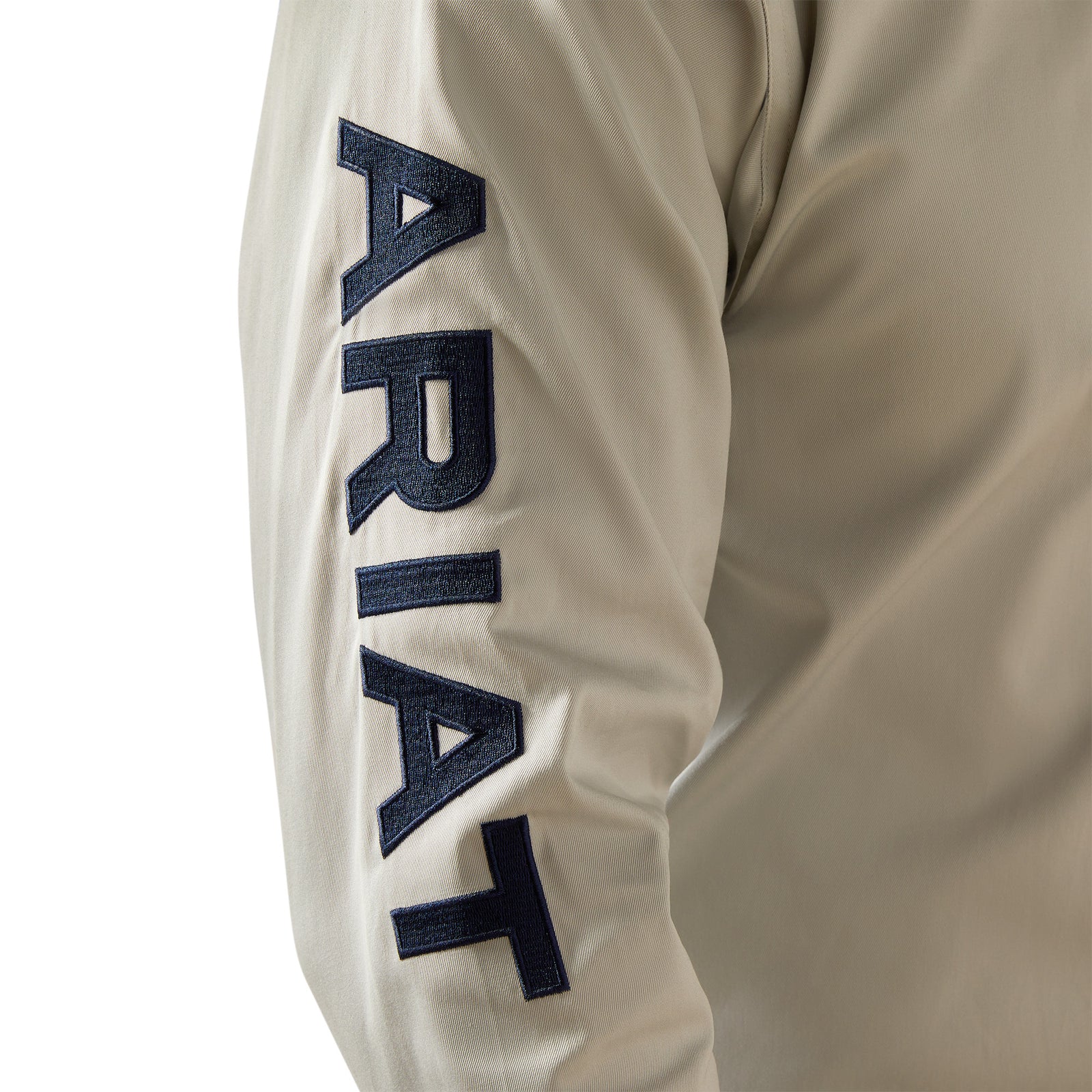 Ariat Men's Team Logo Twill L/S Western Shirt. Beige long-sleeve shirt with 'ARIAT' branding on a white background