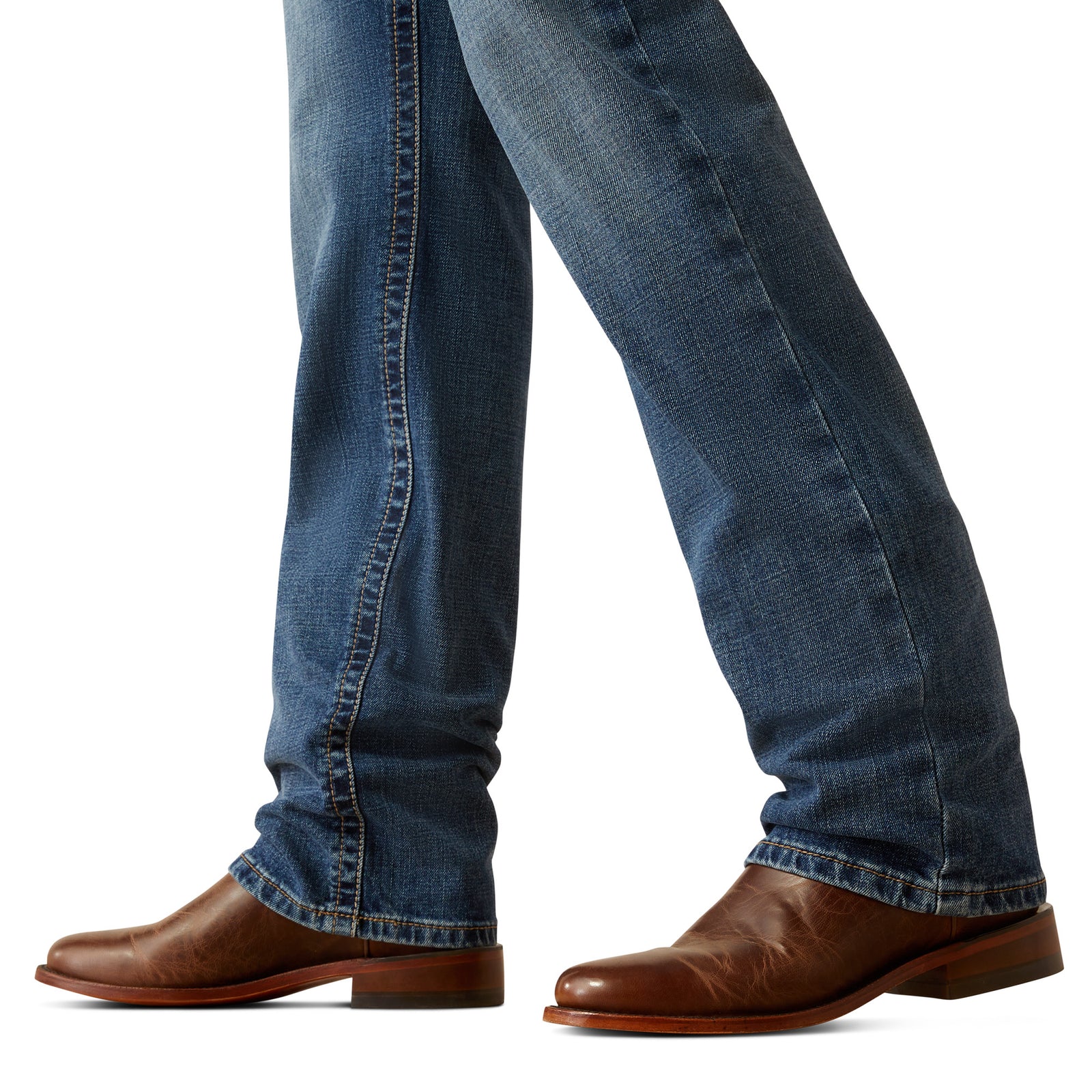 Ariat Men's M7 Travis Straight Leg Jeans. Blue jeans worn with brown shoes on a white background