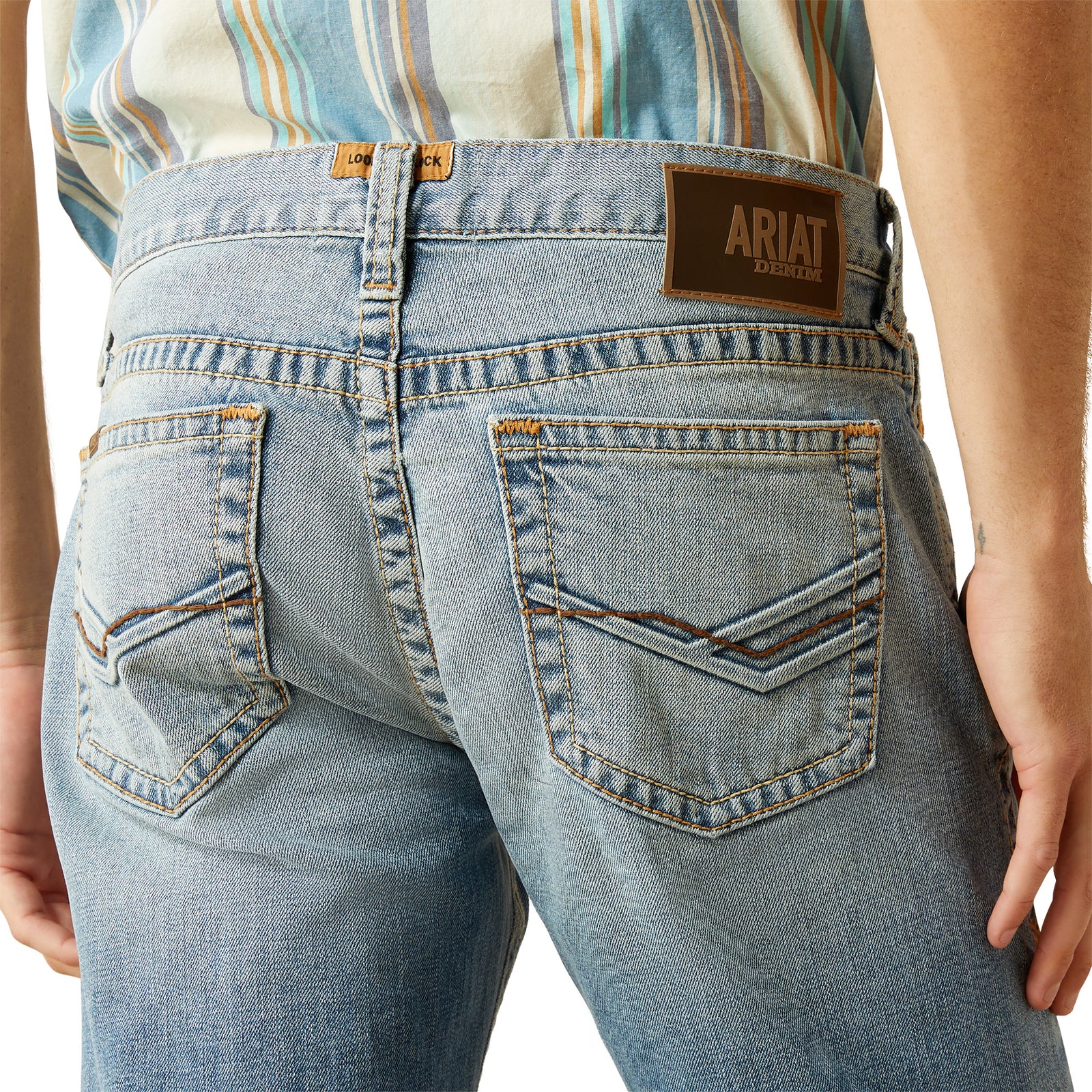 Ariat Men's M7 Tustin Slim Fit Straight Leg Jean. Close-up of blue jeans with Ariat logo on a white background