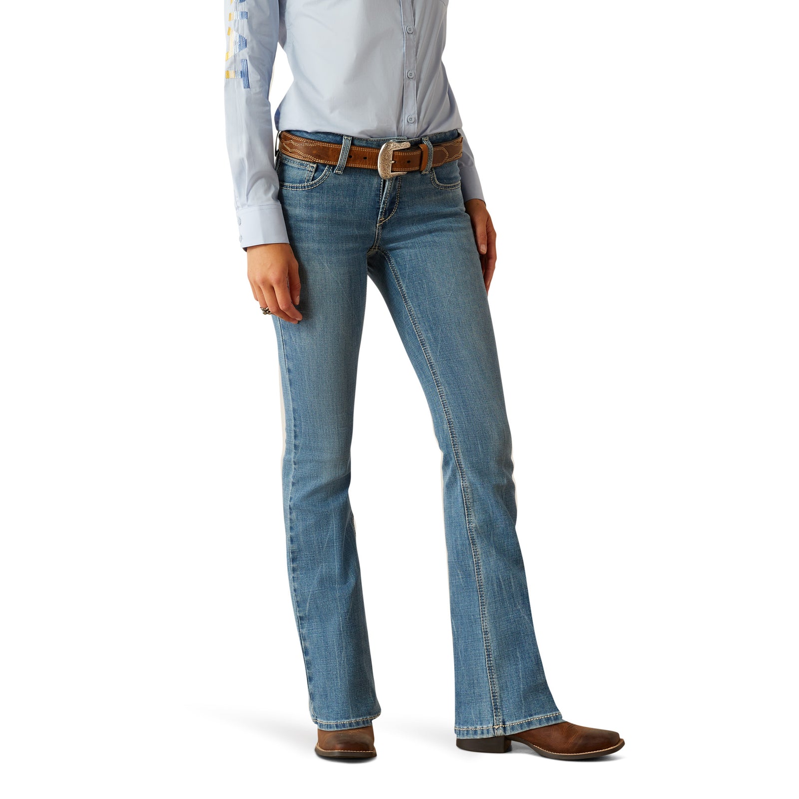 Ariat Women's Naz Perfect Rise Boot Cut Jean. A woman wearing Ariat Women's Naz Perfect Rise Boot Cut Jeans with a pair of boots and a blue shirt.