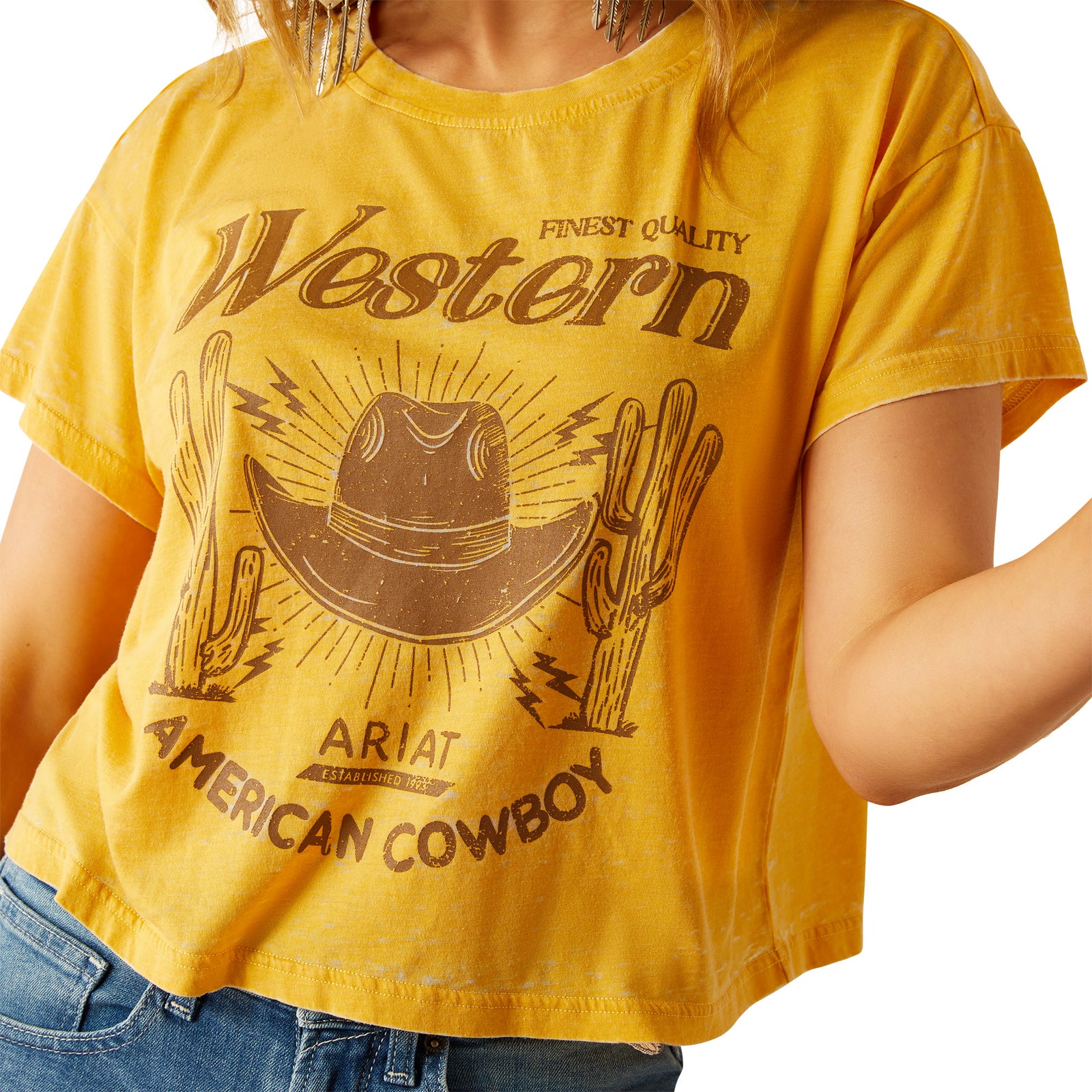Ariat Women's Gold Rush Crop T-Shirt. Yellow t-shirt with 'Western American Cowboy' design and Ariat branding on a white background