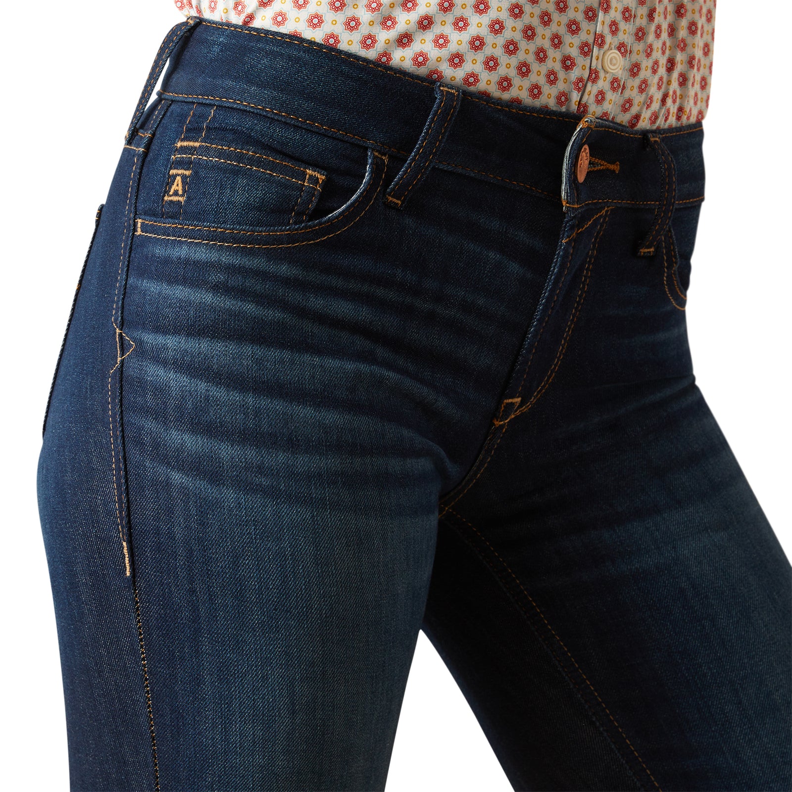 Ariat Women's Juliana Perfect Rise Trouser Jean. Close-up of blue jeans with a patterned shirt underneath on a white background