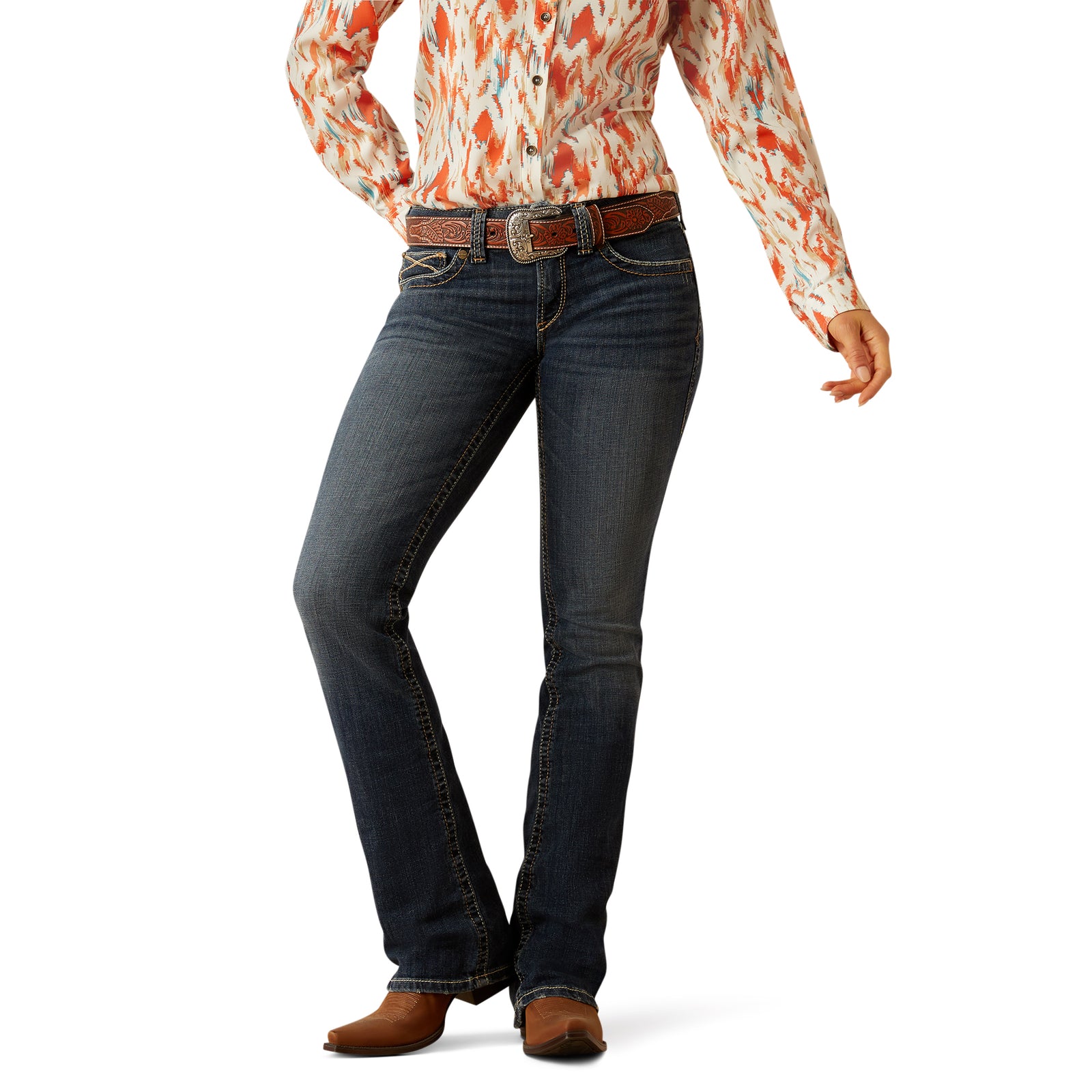 Ariat Women's Lilla Mid Rise Boot Cut Jean. Person wearing blue jeans and a patterned shirt on a white background
