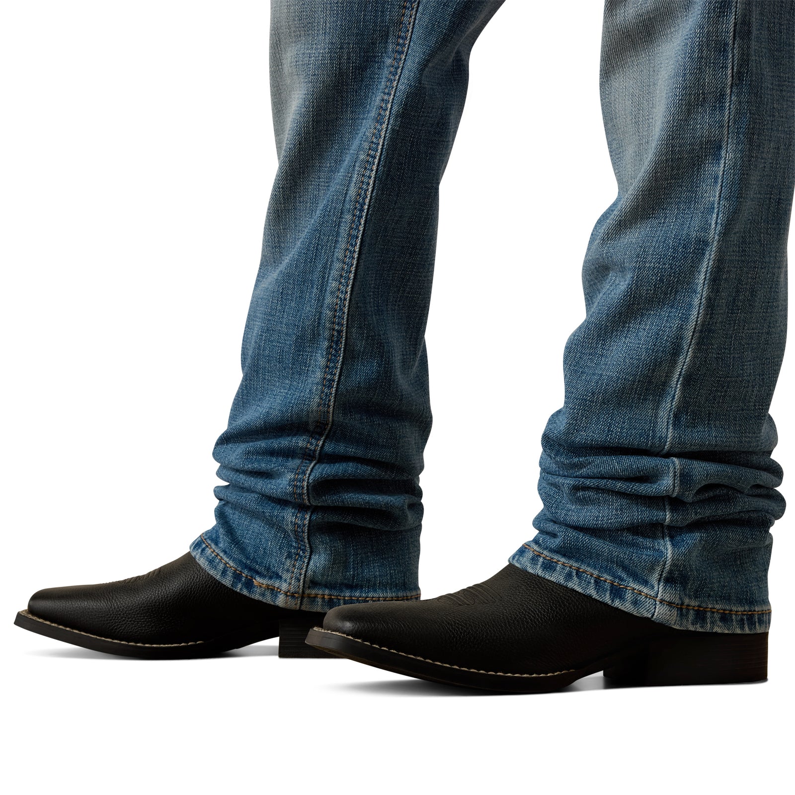 Black cowboy boots worn with blue jeans on a white background