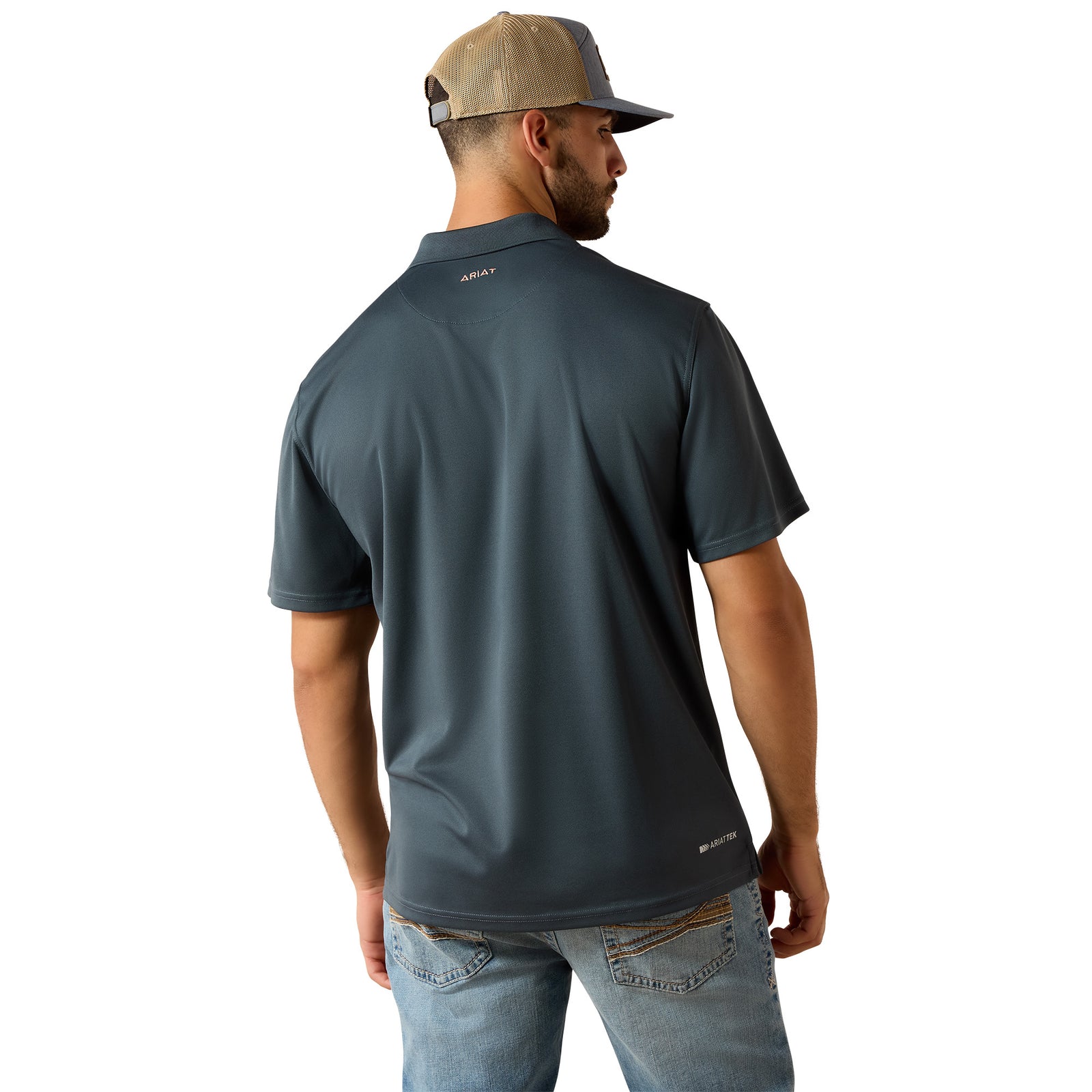 A man wearing a dark slate blue short-sleeve polo shirt from the back, paired with a tan and gray trucker hat and light blue jeans, against a plain white background.