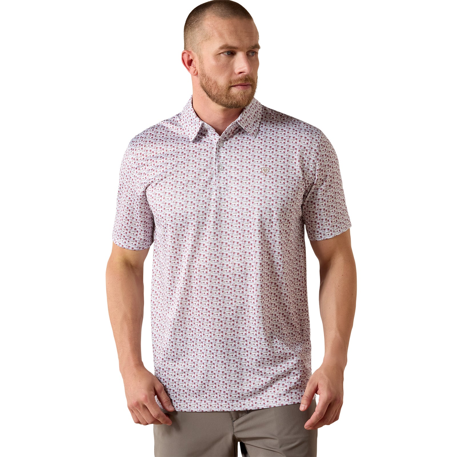 A man wearing a short-sleeve button-up polo shirt with a dense small floral print in red, blue, and green on a white base, paired with gray pants, against a plain white background.