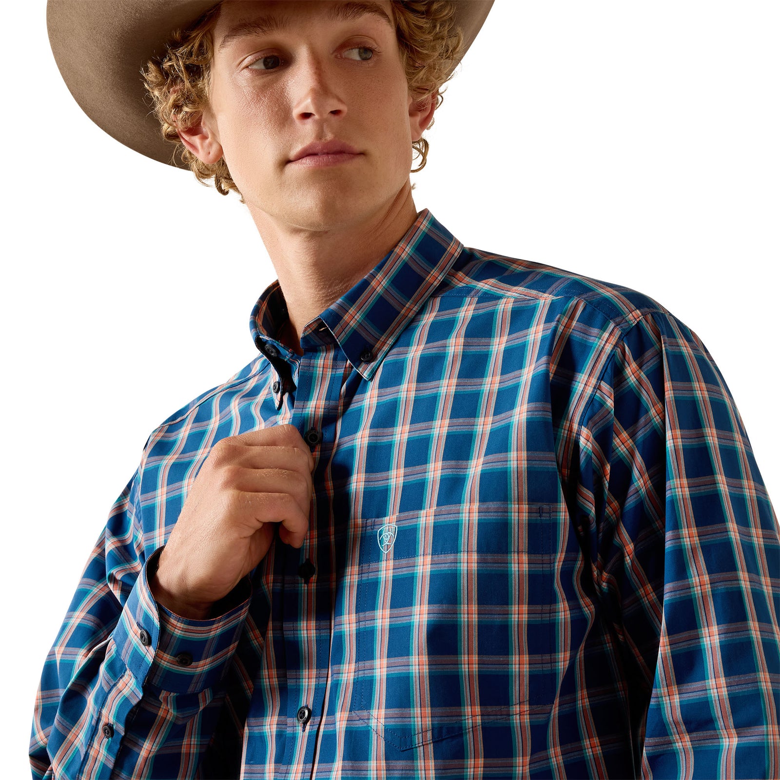 A young man wearing a blue and orange plaid button-down shirt and a cowboy hat, shown from the chest up against a plain white background.