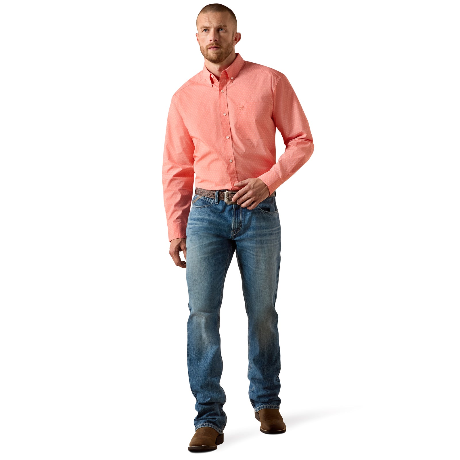Man wearing a pink shirt and blue jeans standing against a white background