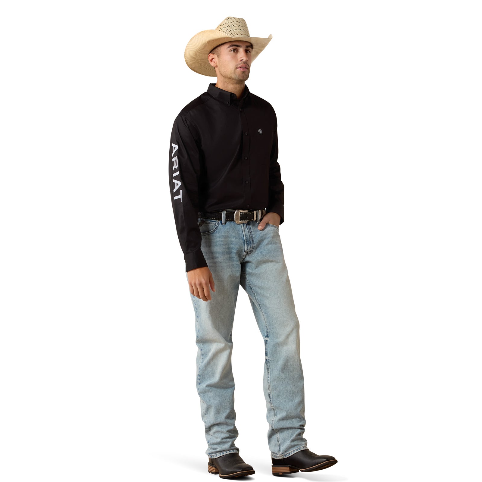 Man wearing a black Ariat shirt, light blue jeans, and a cowboy hat on a white background