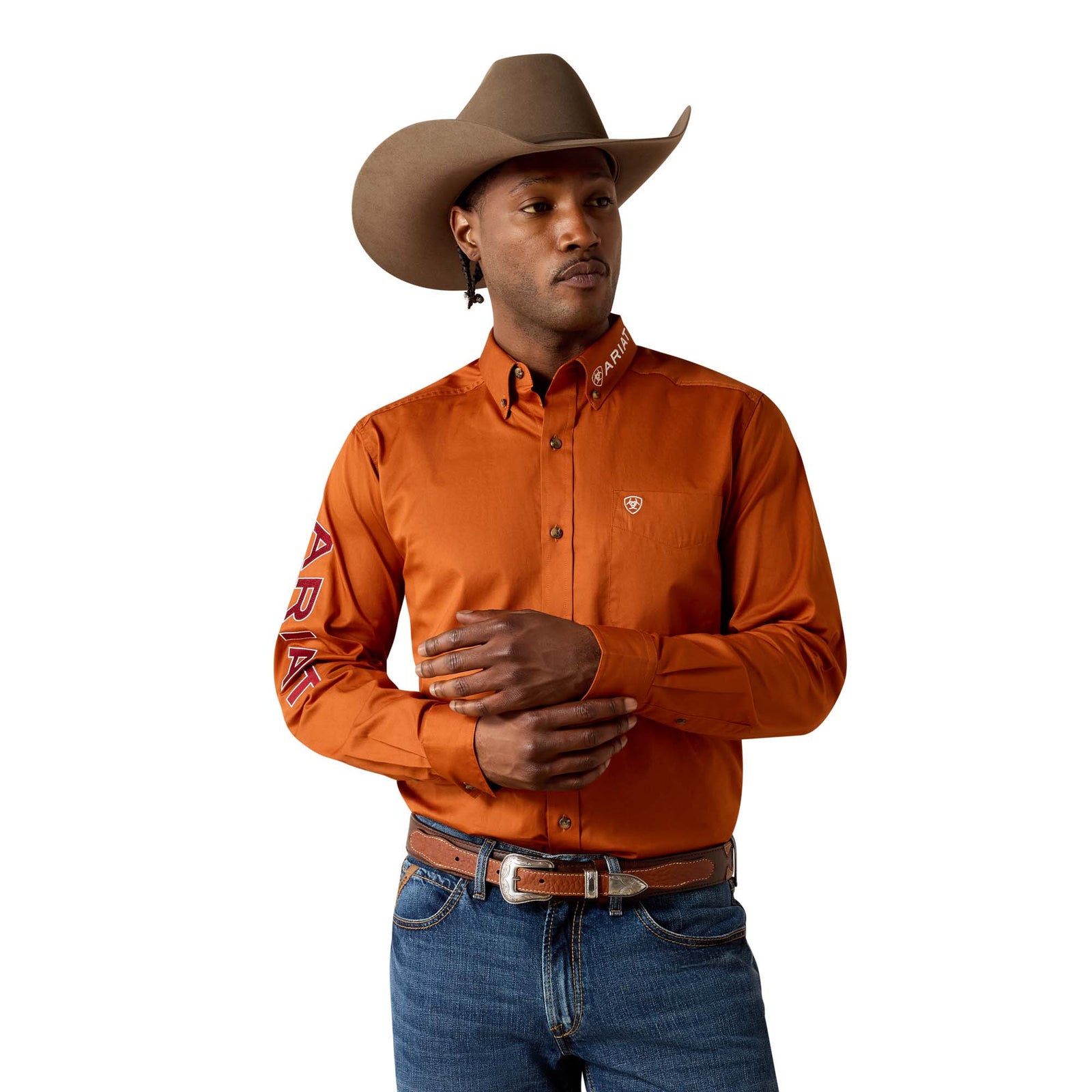 Man wearing an orange shirt, blue jeans, and a brown cowboy hat on a white background
