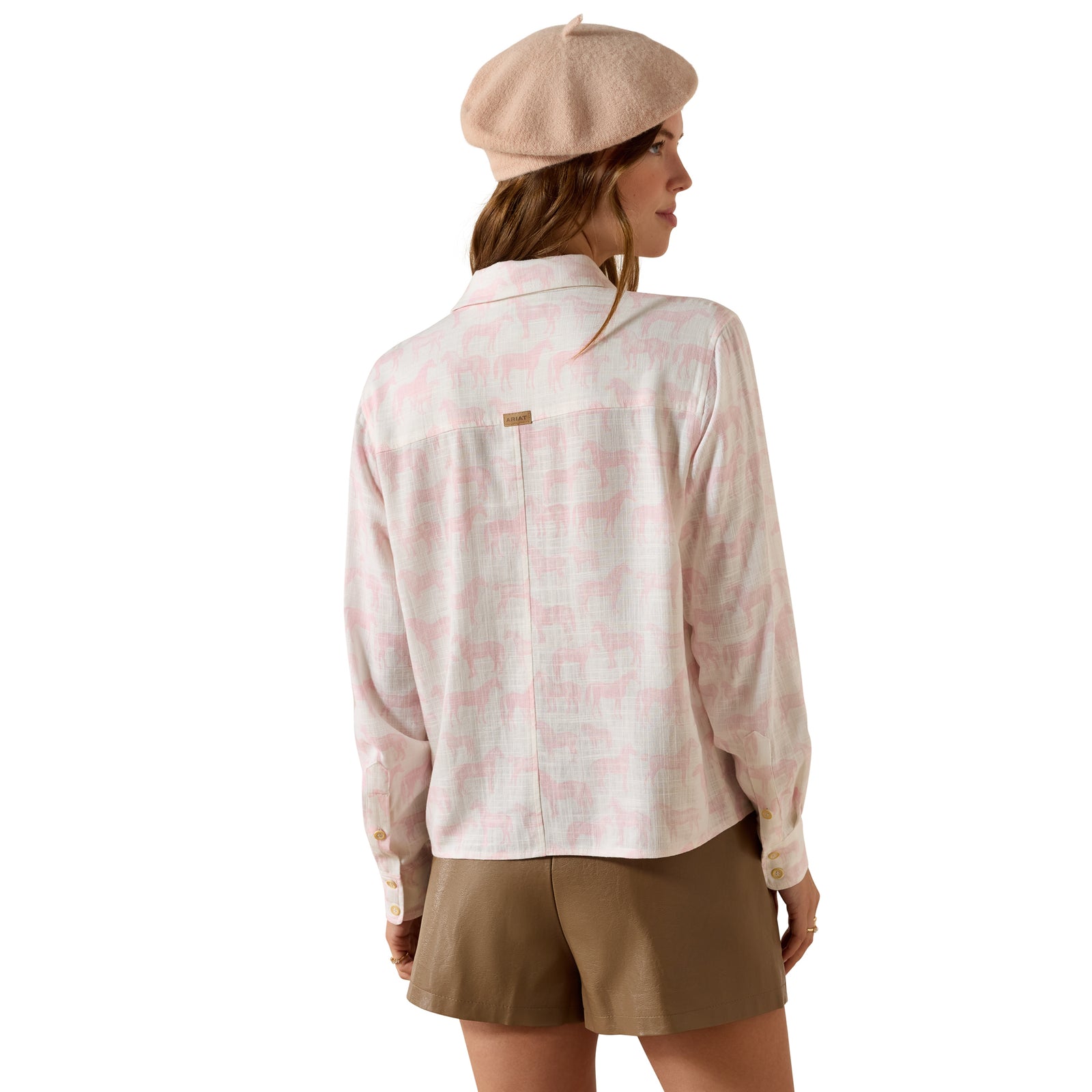 Woman wearing a patterned shirt and beige beret on a white background