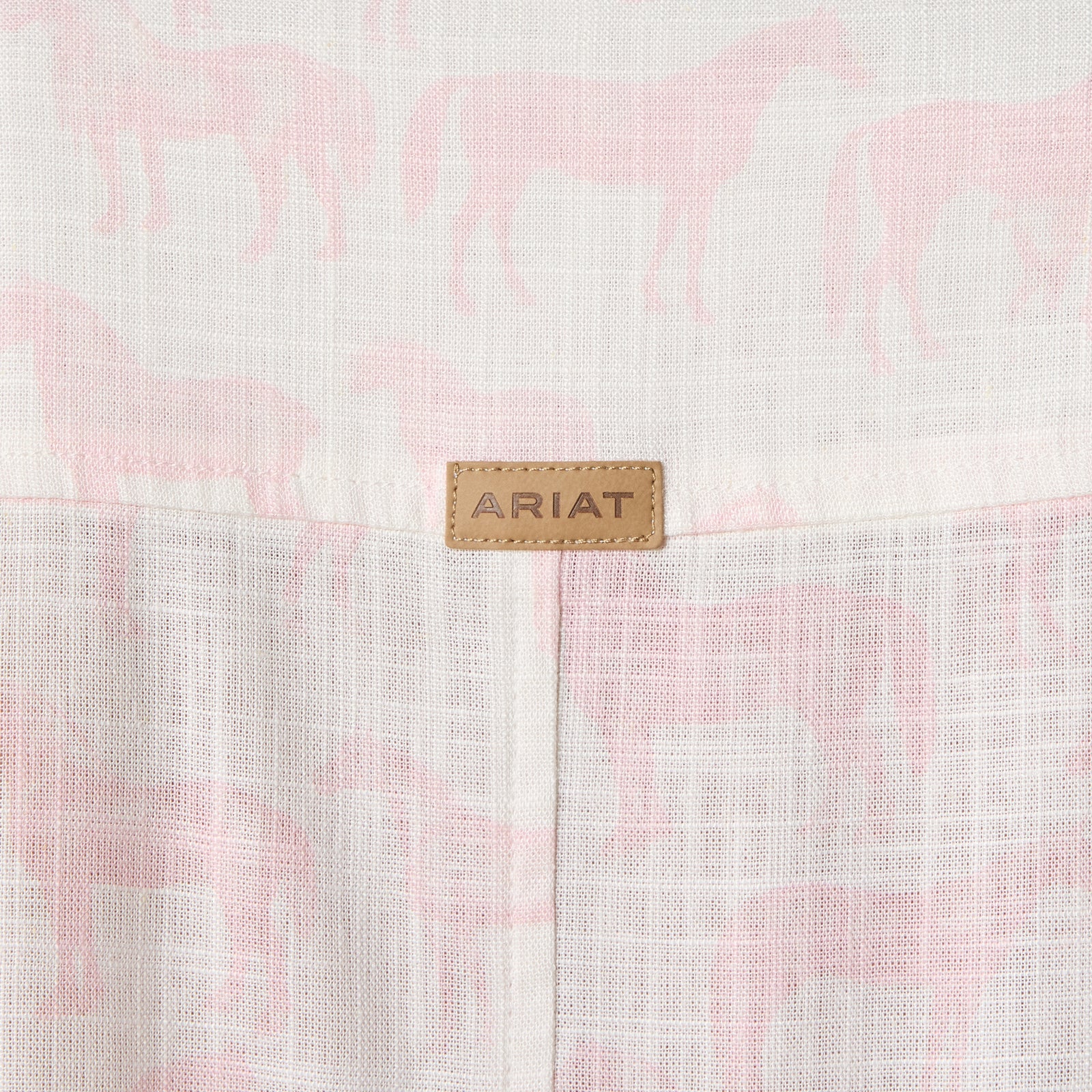 Close-up of a pink and white checkered fabric with an Ariat logo tag.