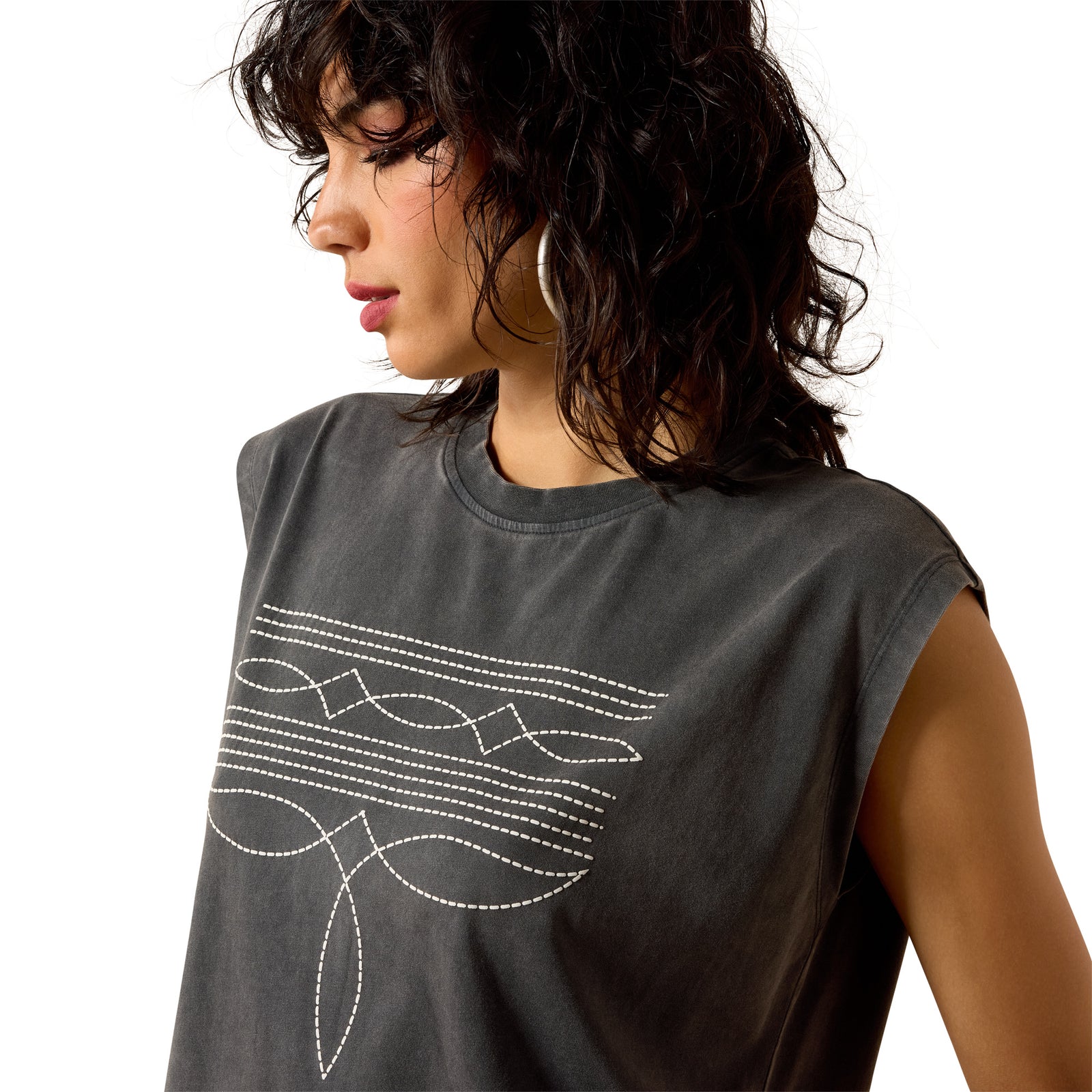 Woman wearing a gray sleeveless top with white embroidery on a white background