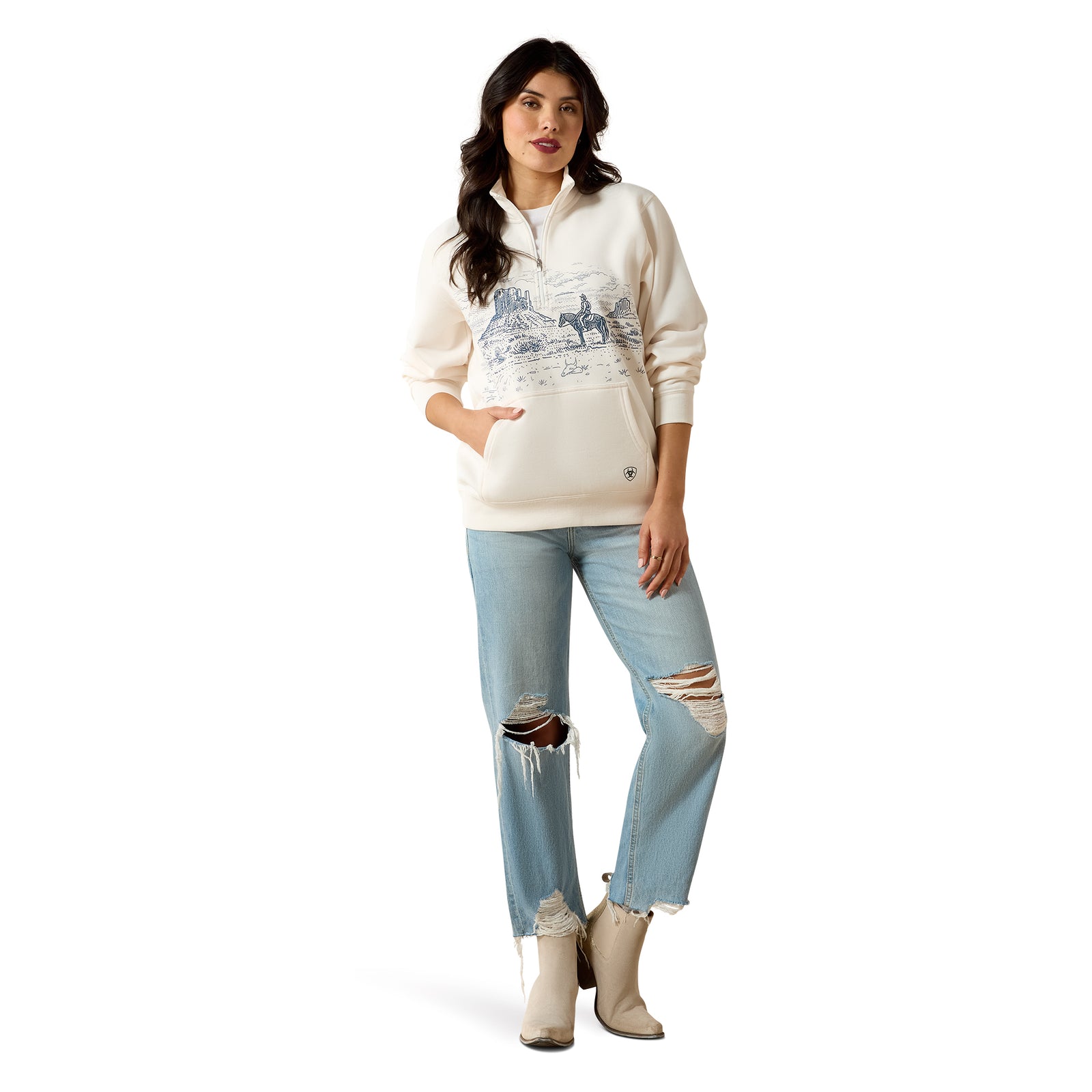 Woman wearing a cream-colored sweater with a graphic design and light blue jeans on a white background