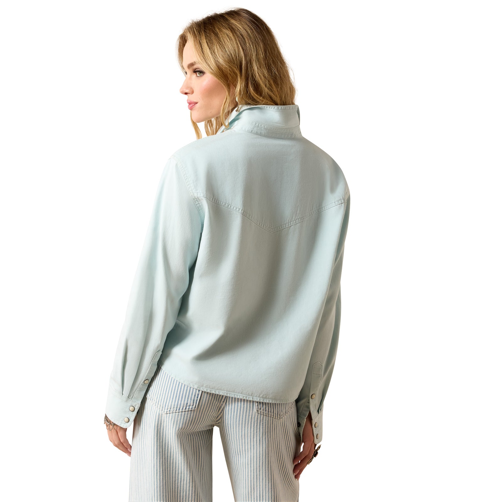 Woman wearing a light blue shirt and white pants on a white background