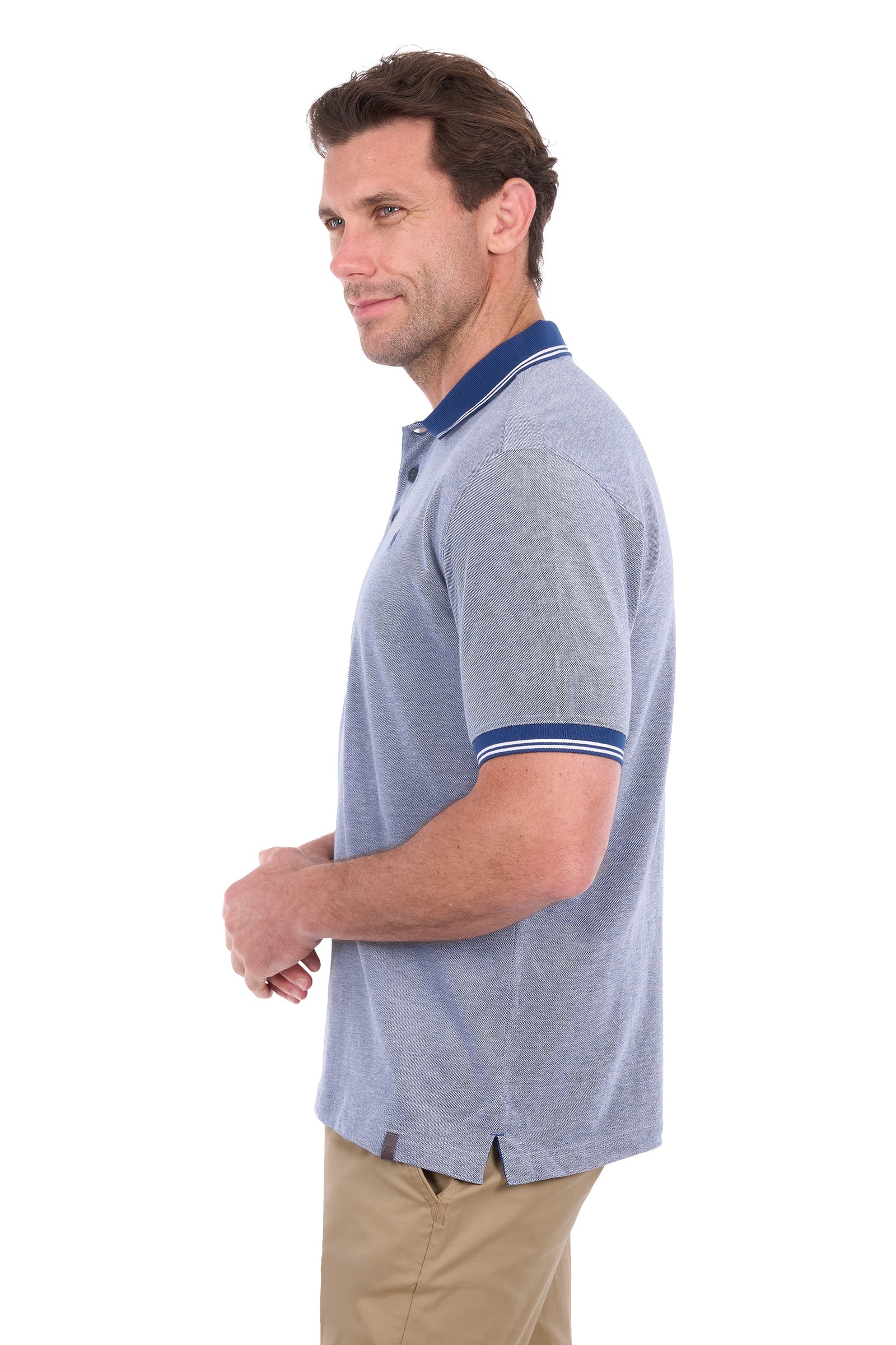 A man shown in profile wearing a light heather gray polo shirt with a navy blue collar and sleeve trim, paired with khaki pants, against a plain white background.