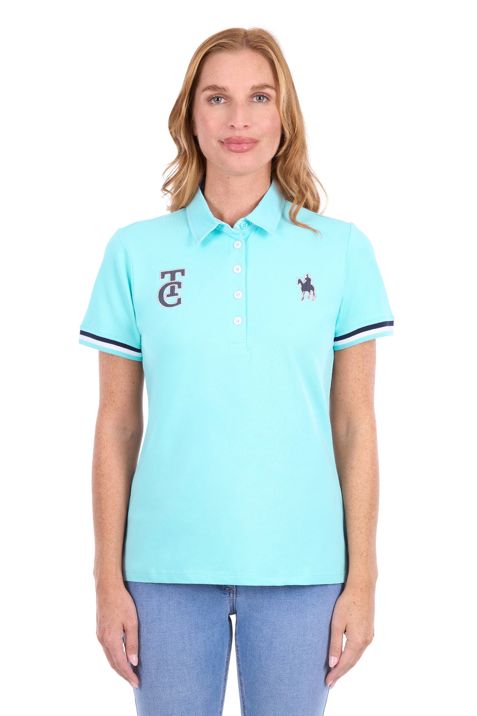 A woman modeling a light aqua blue short-sleeve polo shirt with a navy embroidered logo on the left chest and navy stripe accents on the sleeve cuffs, paired with blue jeans against a plain white background.