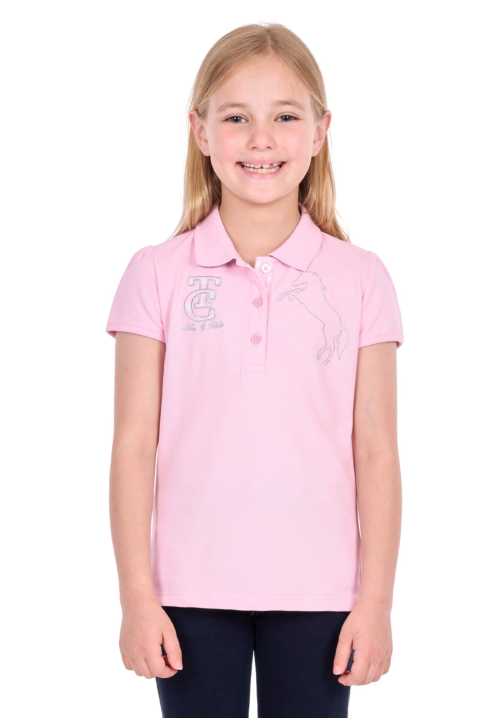 A young girl with blonde hair smiling, wearing a light pink short-sleeve polo shirt with white embroidered graphics on the chest, paired with dark pants, against a plain white background.