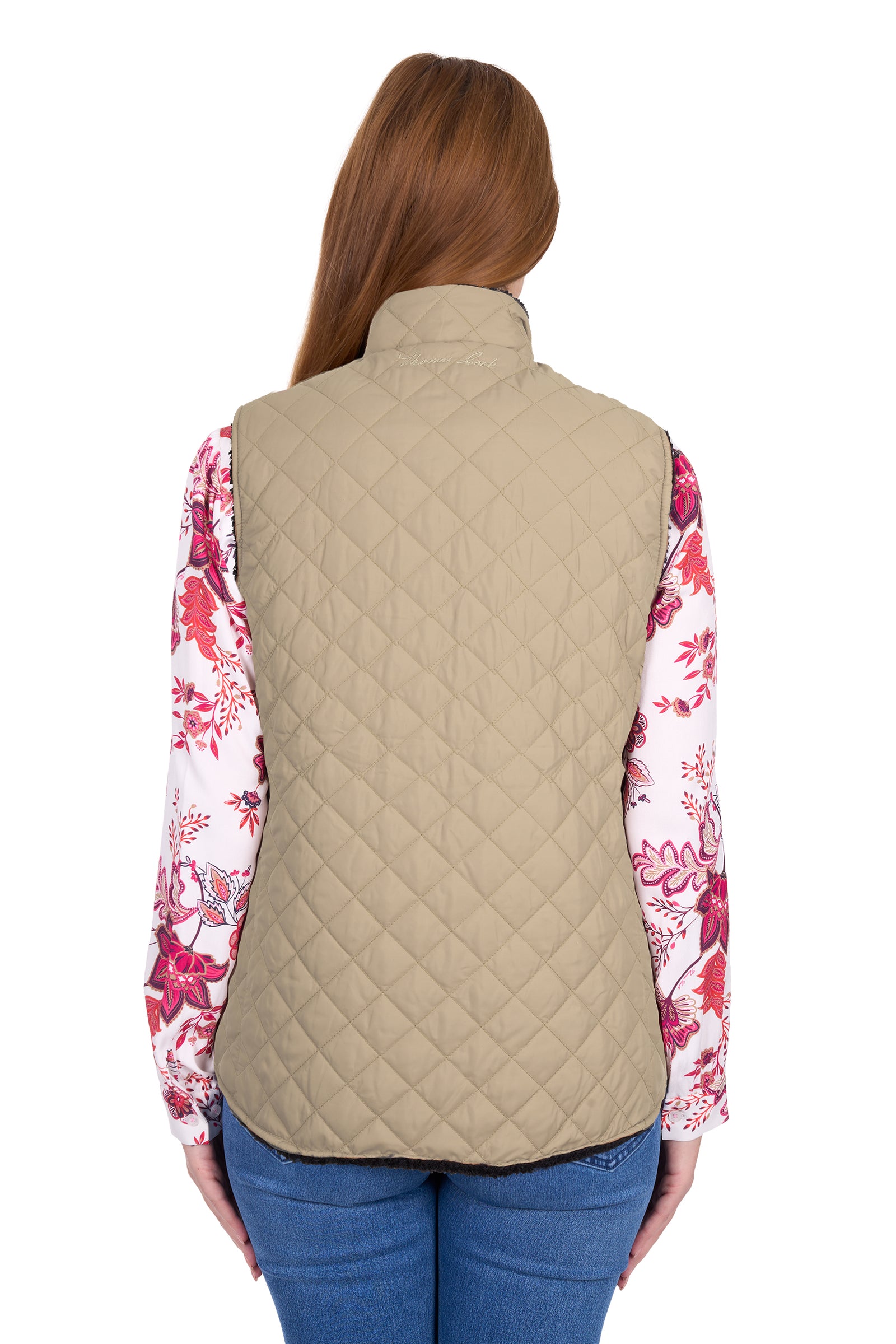 Person wearing a beige quilted vest over a floral shirt on a white background