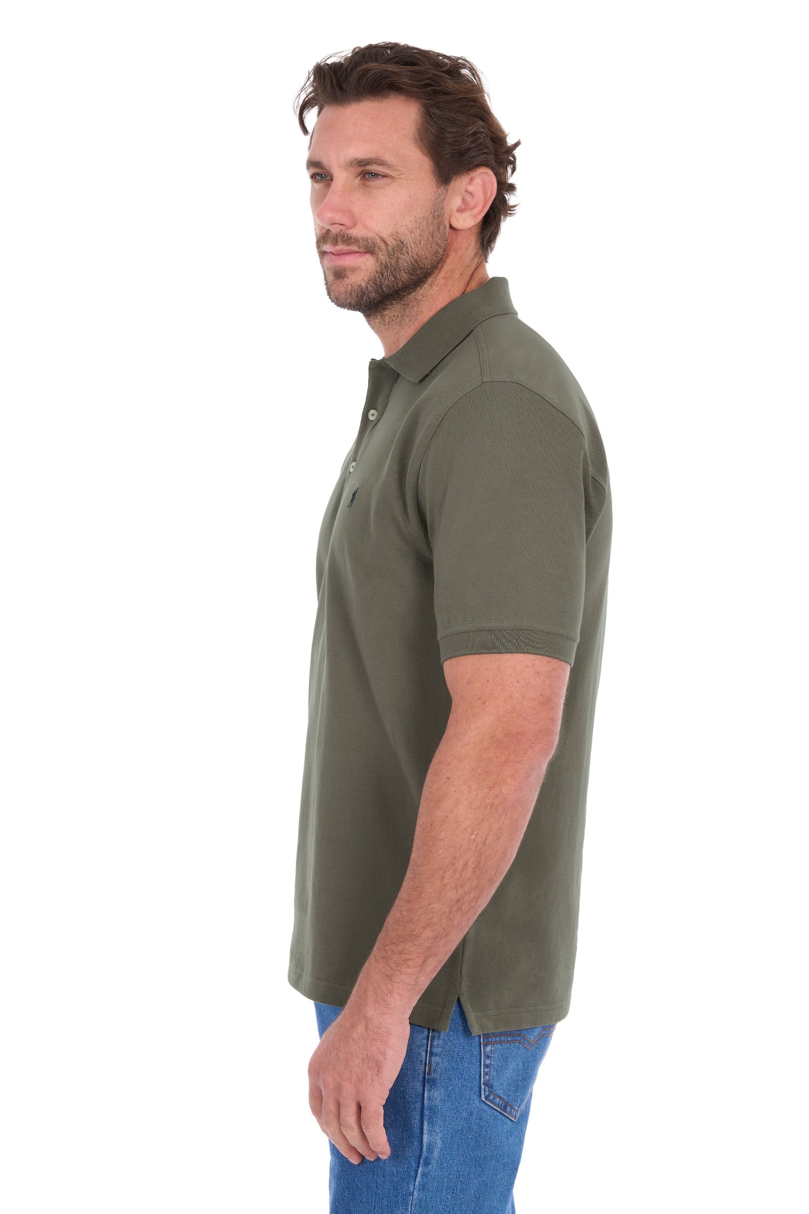 A man shown in profile wearing a short-sleeve polo shirt in olive green, paired with blue jeans, against a plain white background.