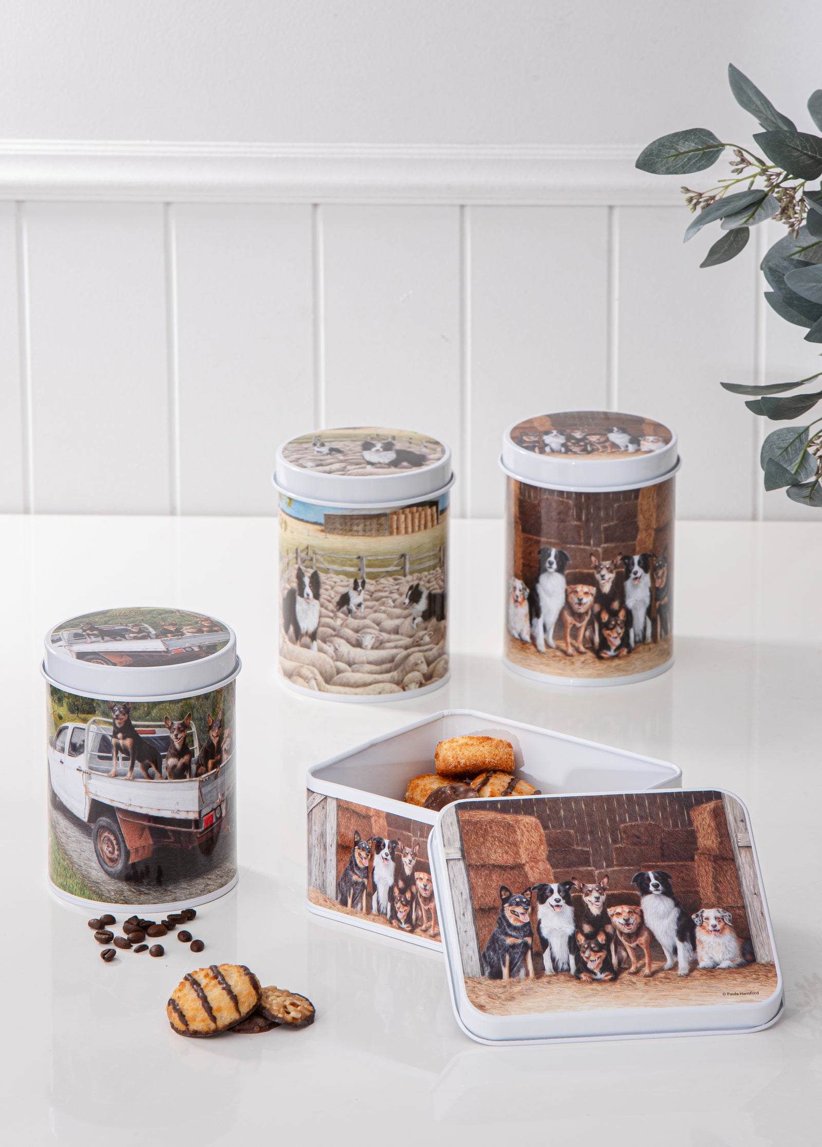 Decorative cookie tins with printed images on a white surface.