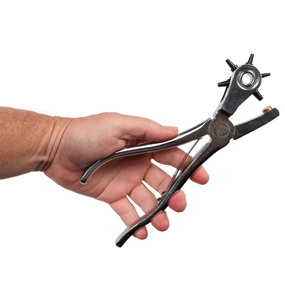 SS Deluxe Leather Punch. Hand holding a metal hole punch against a white background