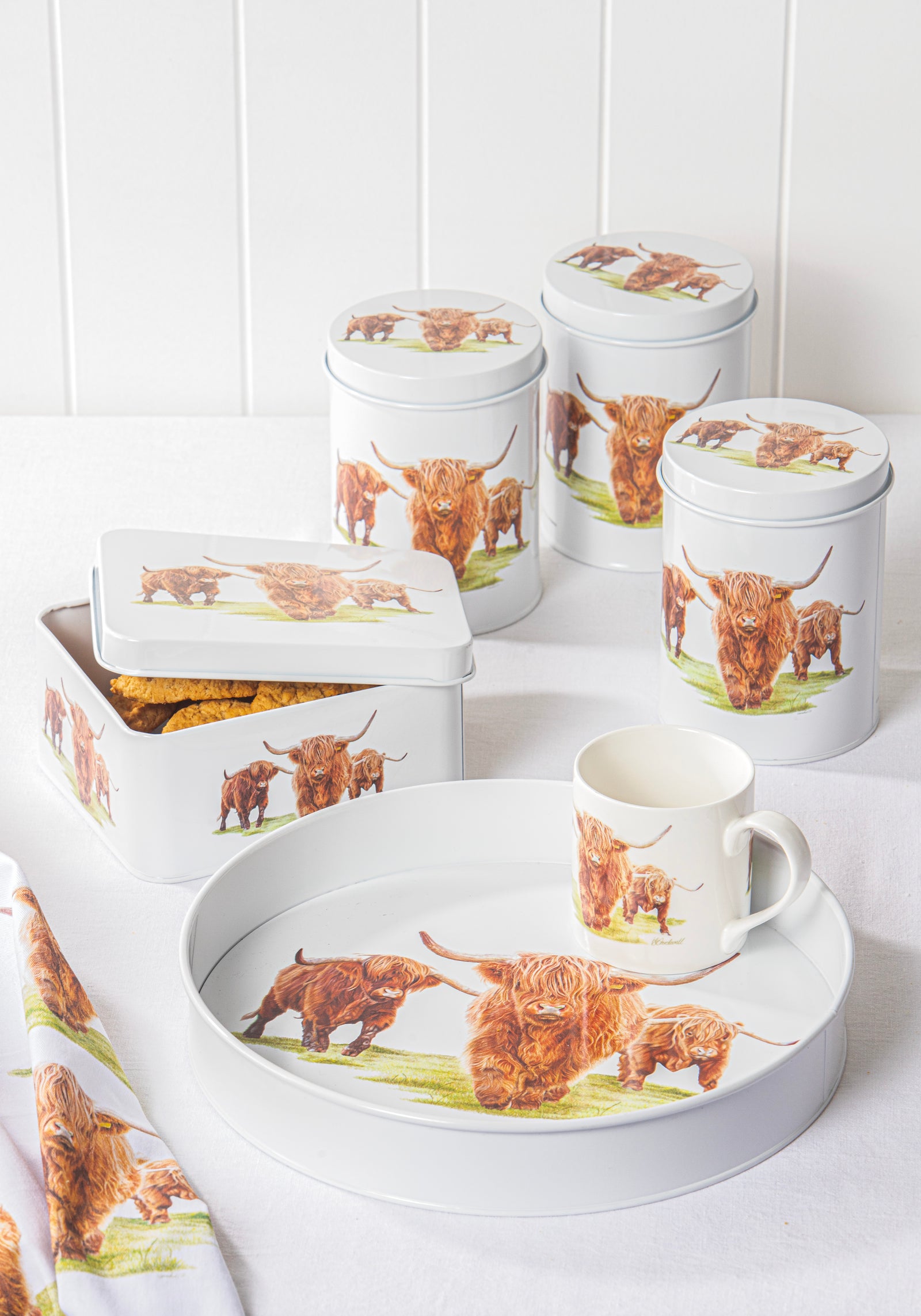 Set of kitchen containers and a mug with highland cow design on a white surface.