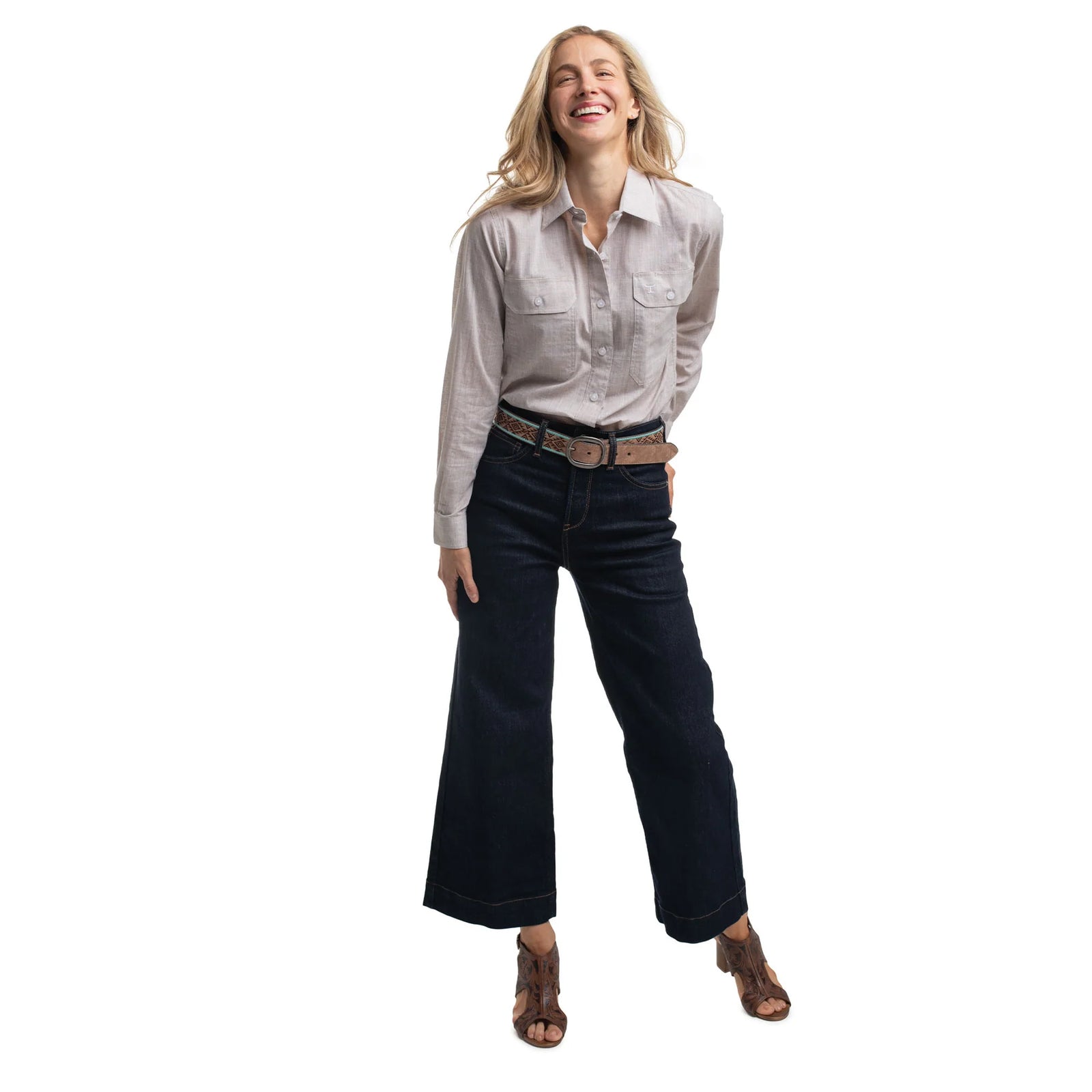 Woman wearing a light-colored shirt and dark jeans on a white background