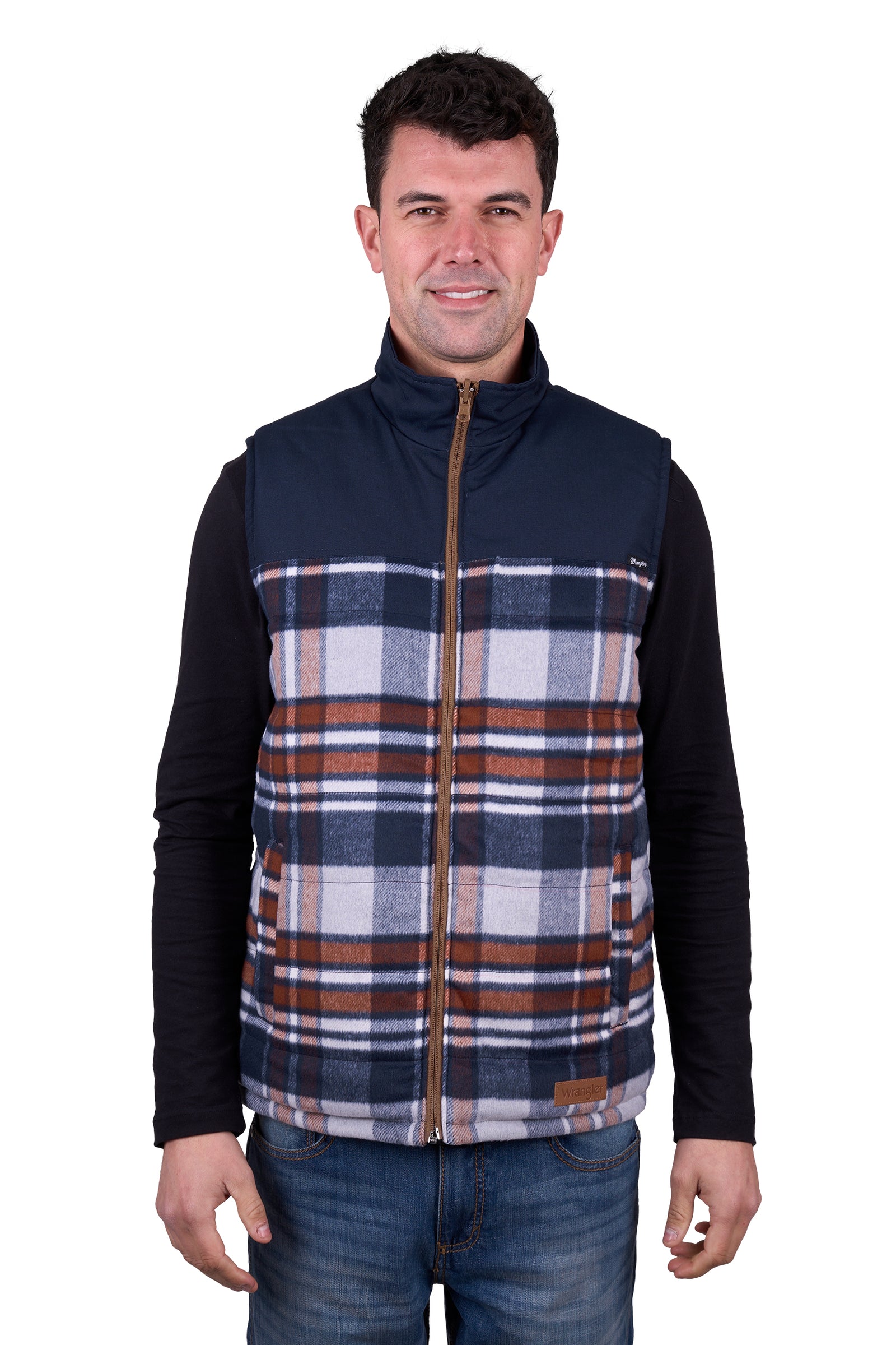 A man wearing a Wrangler Men's Koda Reversible Vest in navy and beige colors, paired with a black shirt and blue jeans.