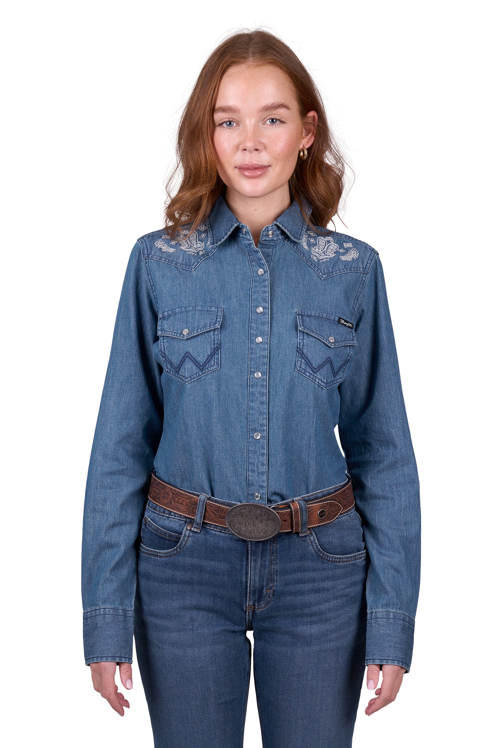 A woman wearing a wrangler western embroidered demim western shirt with paired with blue jeans.
