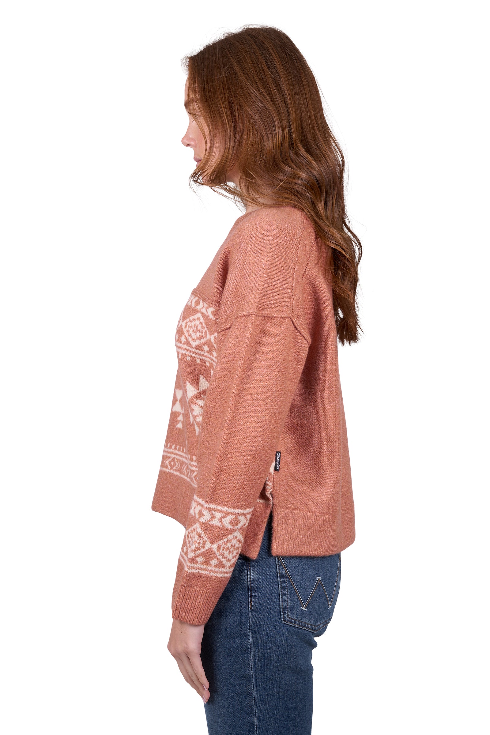 A woman wearing awrangler western peach crew neck jumper with a geometric pattern and rib trim, paired with blue jeans.