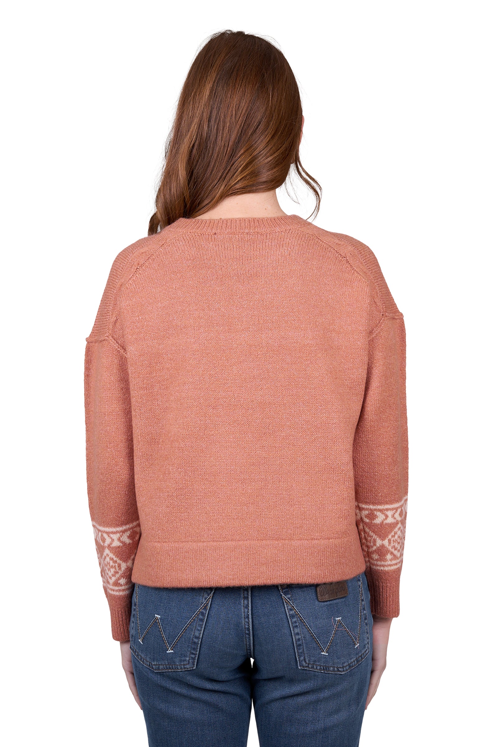 A woman wearing awrangler western peach crew neck jumper with a geometric pattern and rib trim, paired with blue jeans.