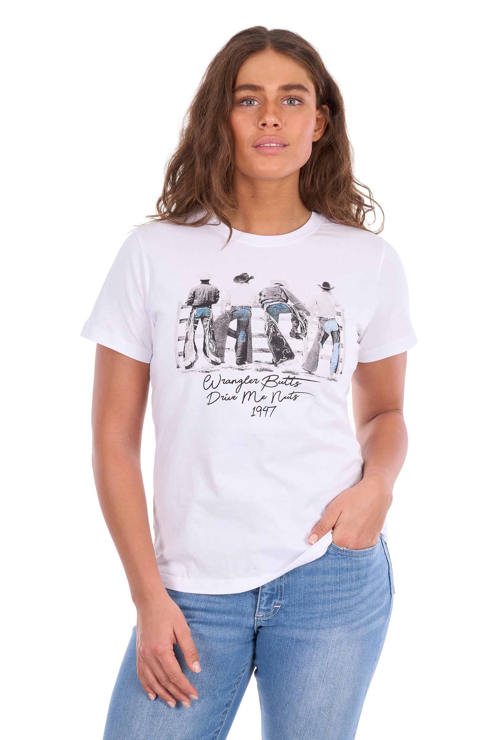 A woman modeling a white short-sleeve graphic t-shirt with a black and white western rider print and text reading 'Wrangler Boots Daze My Nuts 1947', paired with blue jeans against a plain white background.