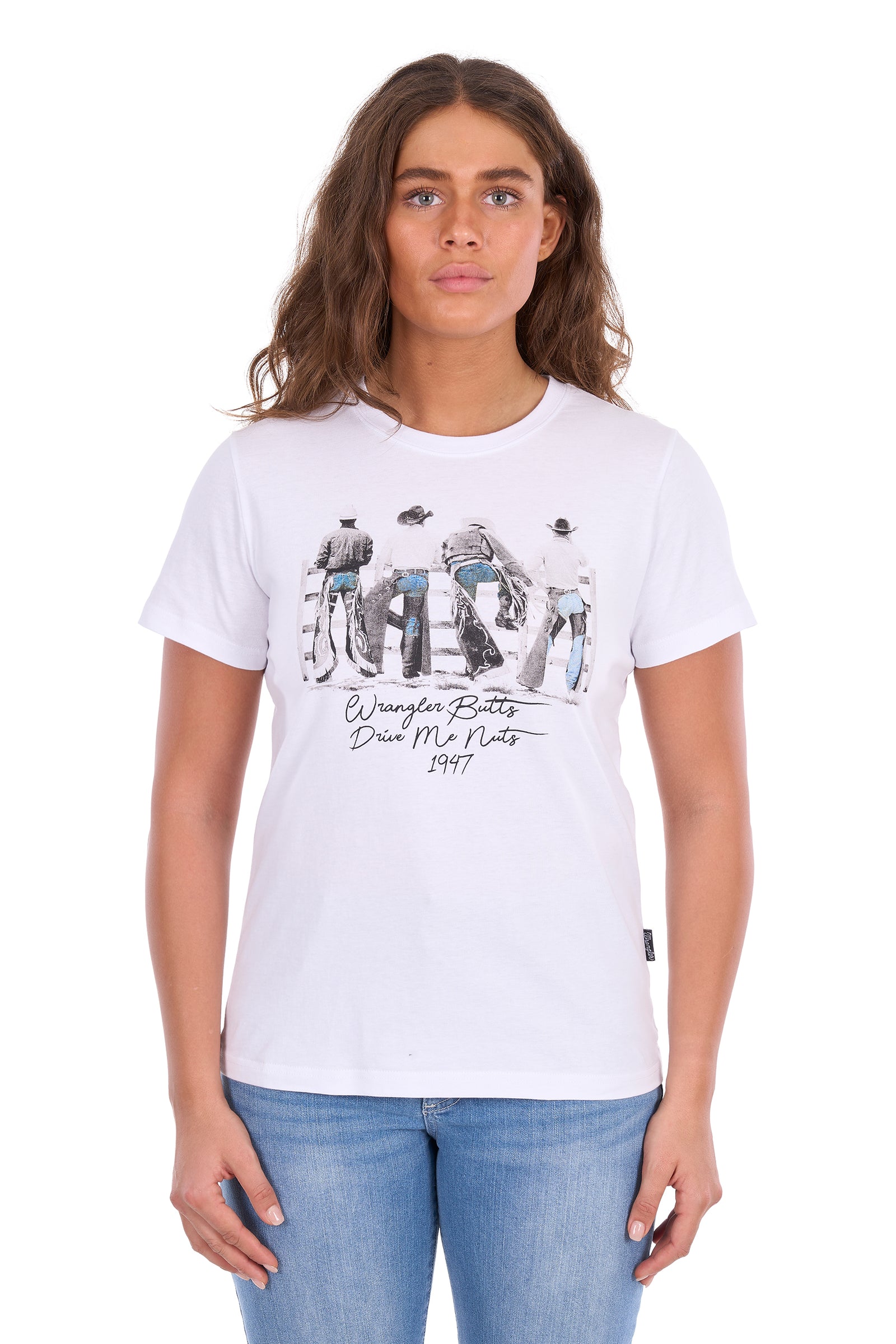 A woman modeling a white graphic t-shirt with a black and blue print of Jim Morrison and the text 'By Your Boots Die My Boots 1977', paired with blue jeans against a plain white background.