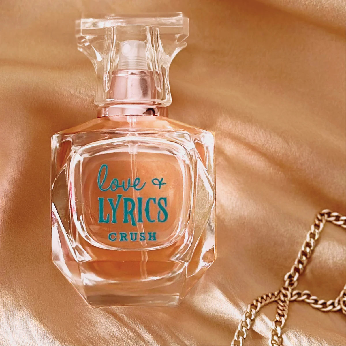 Perfume bottle labeled 'Love & Lyrics Crush' on a gold fabric background