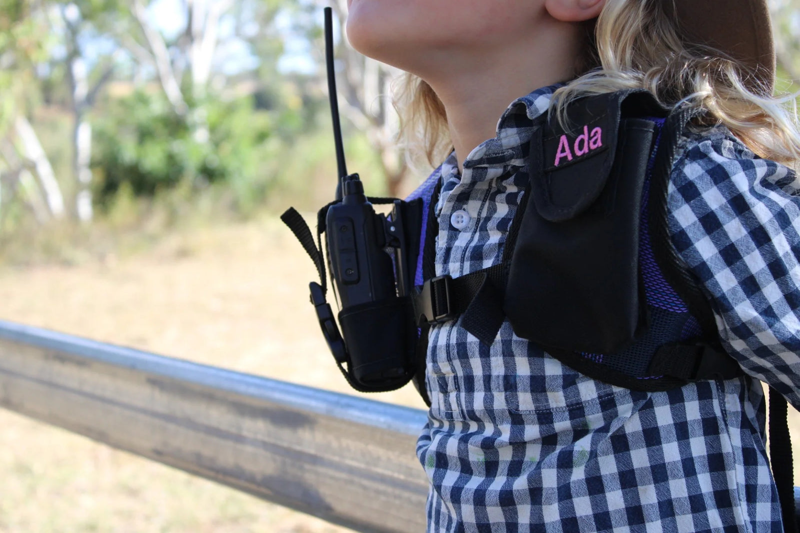 Person wearing a backpack with a walkie-talkie, outdoors.