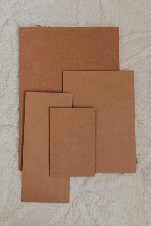 Here And Then Box - Natural. Set of brown cardboard sheets on a textured beige surface