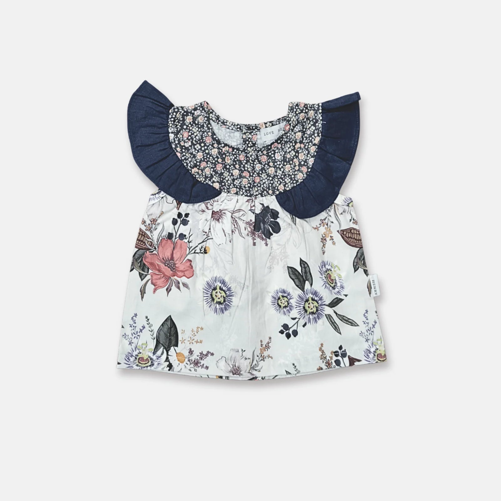 A baby girl's short-sleeve dress with a white floral print body, a navy blue ruffled collar, and a matching navy smocked yoke with a small floral pattern.