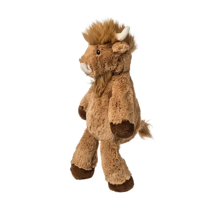 Plush toy cow with brown fur and white horns on a white background