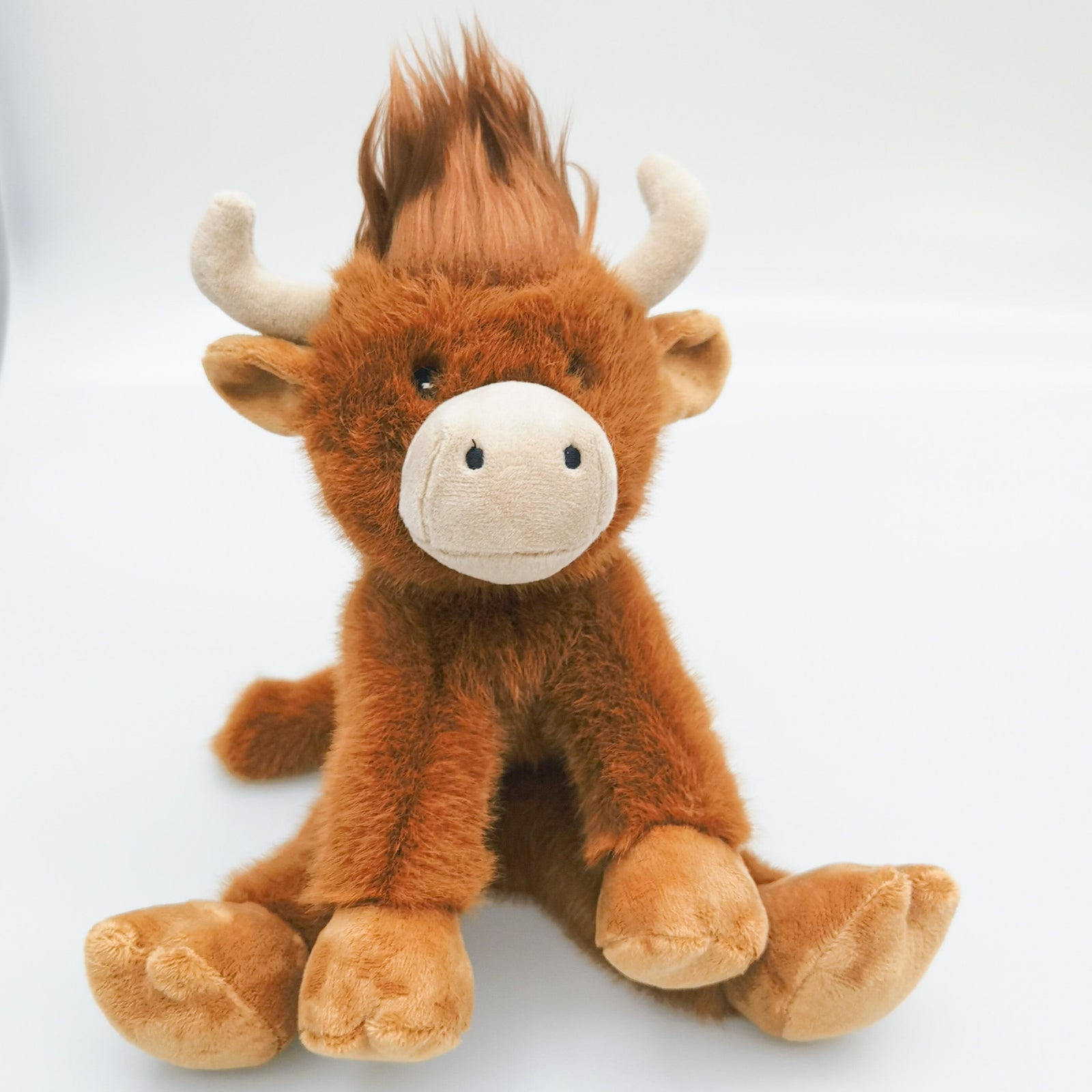 UB411116. Plush toy cow with brown fur and white horns on a light gray background