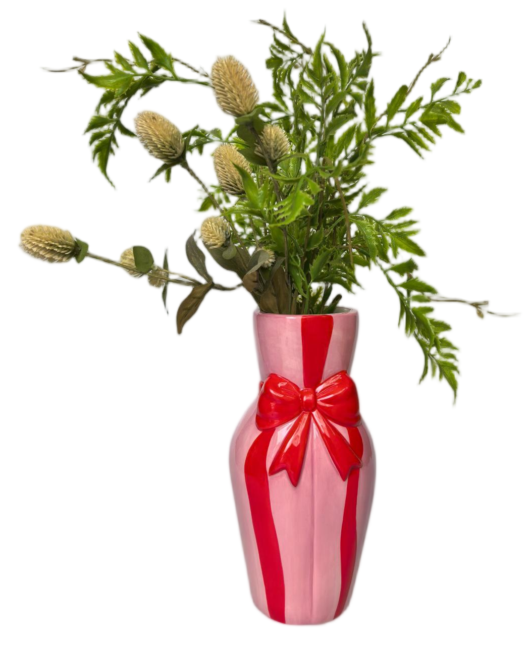 An artificial floral arrangement with green leaves and beige flower buds displayed in a pink ceramic vase with bold red vertical stripes and a red bow, isolated on a white background.